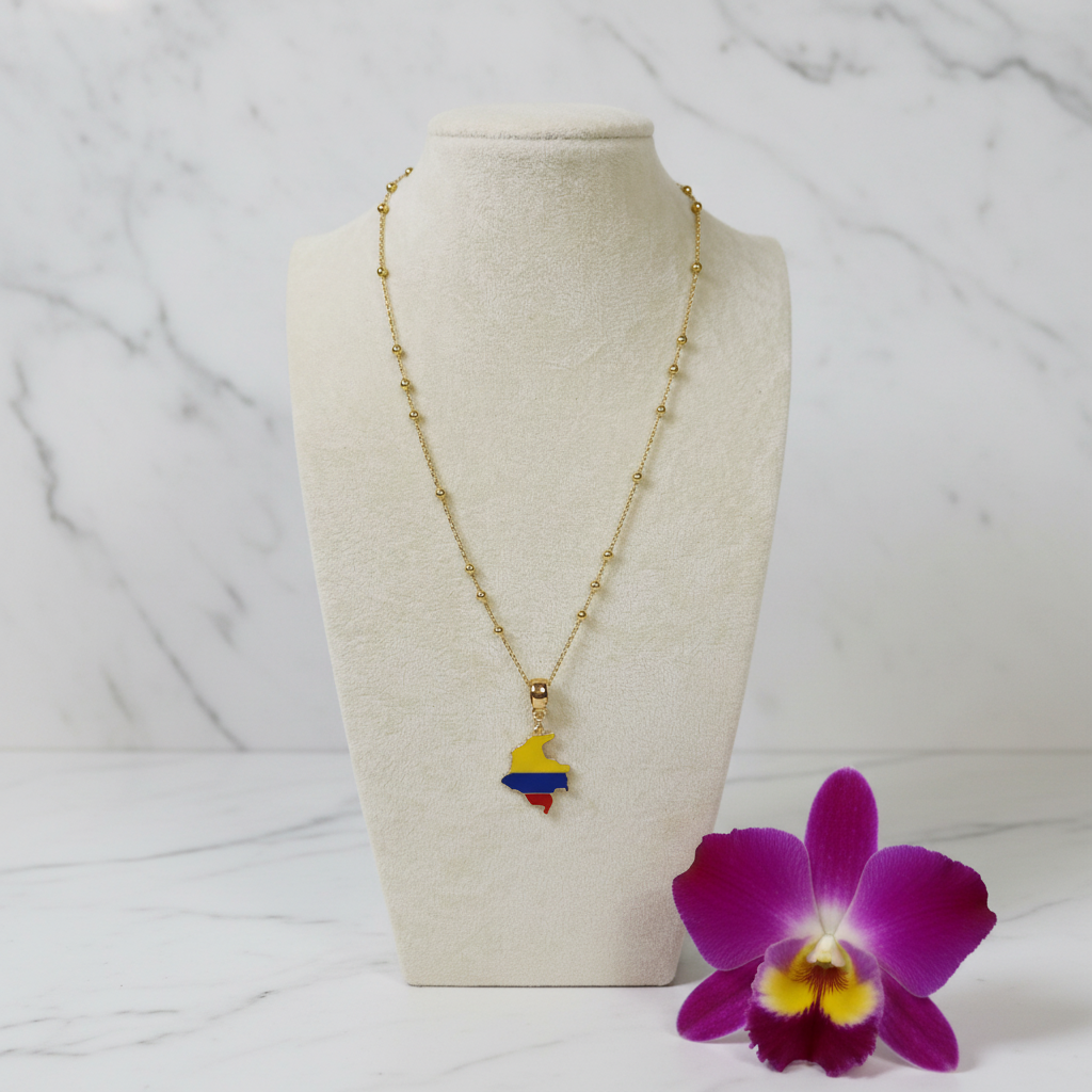 The Bacatá Necklace from Chica Chica Jewelry with Colombian map pendant on a mannequin bust, accompanied by a purple orchid on a marble background.