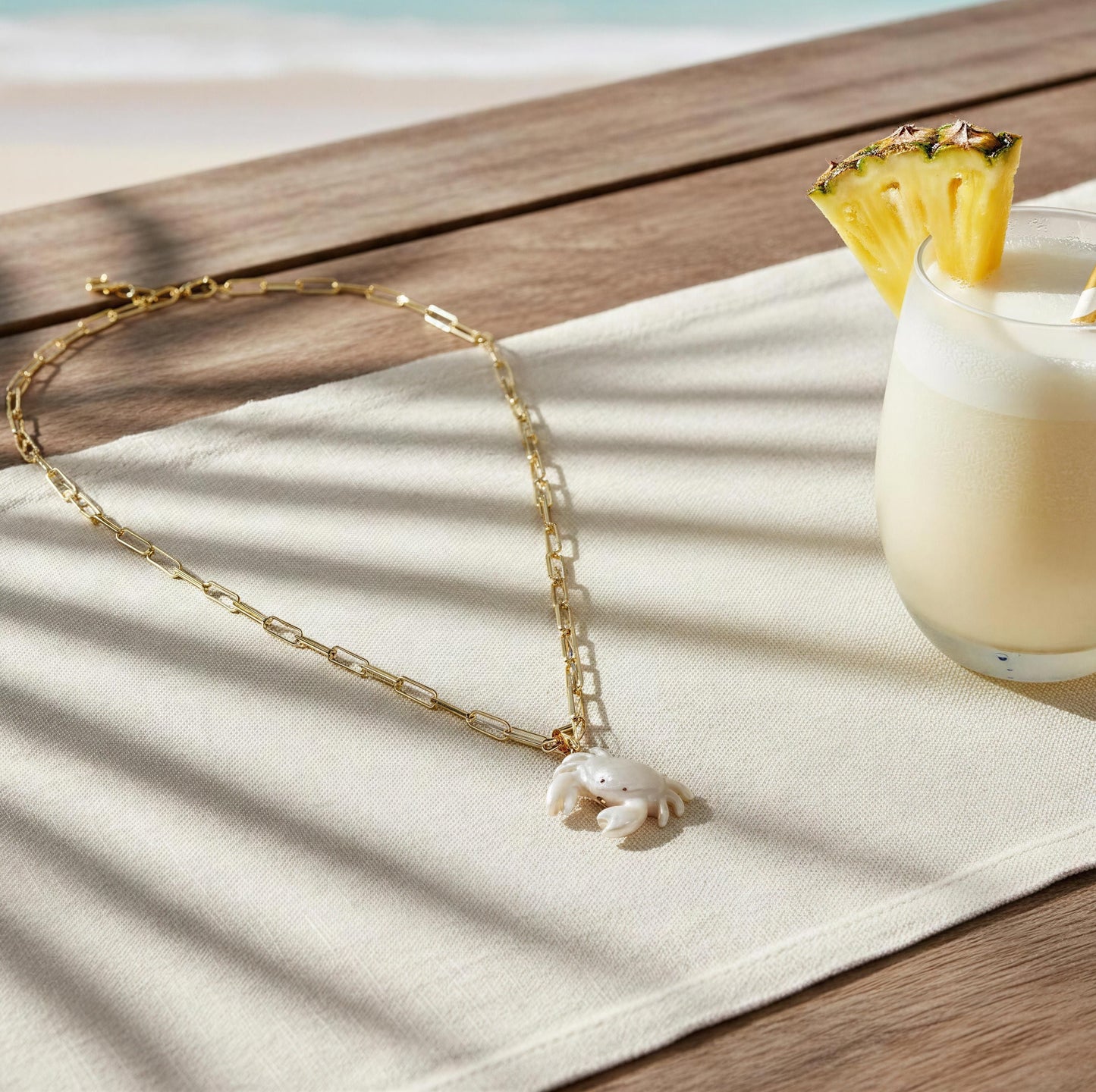 The Brisa Crab Necklace on a white cloth with a beach background