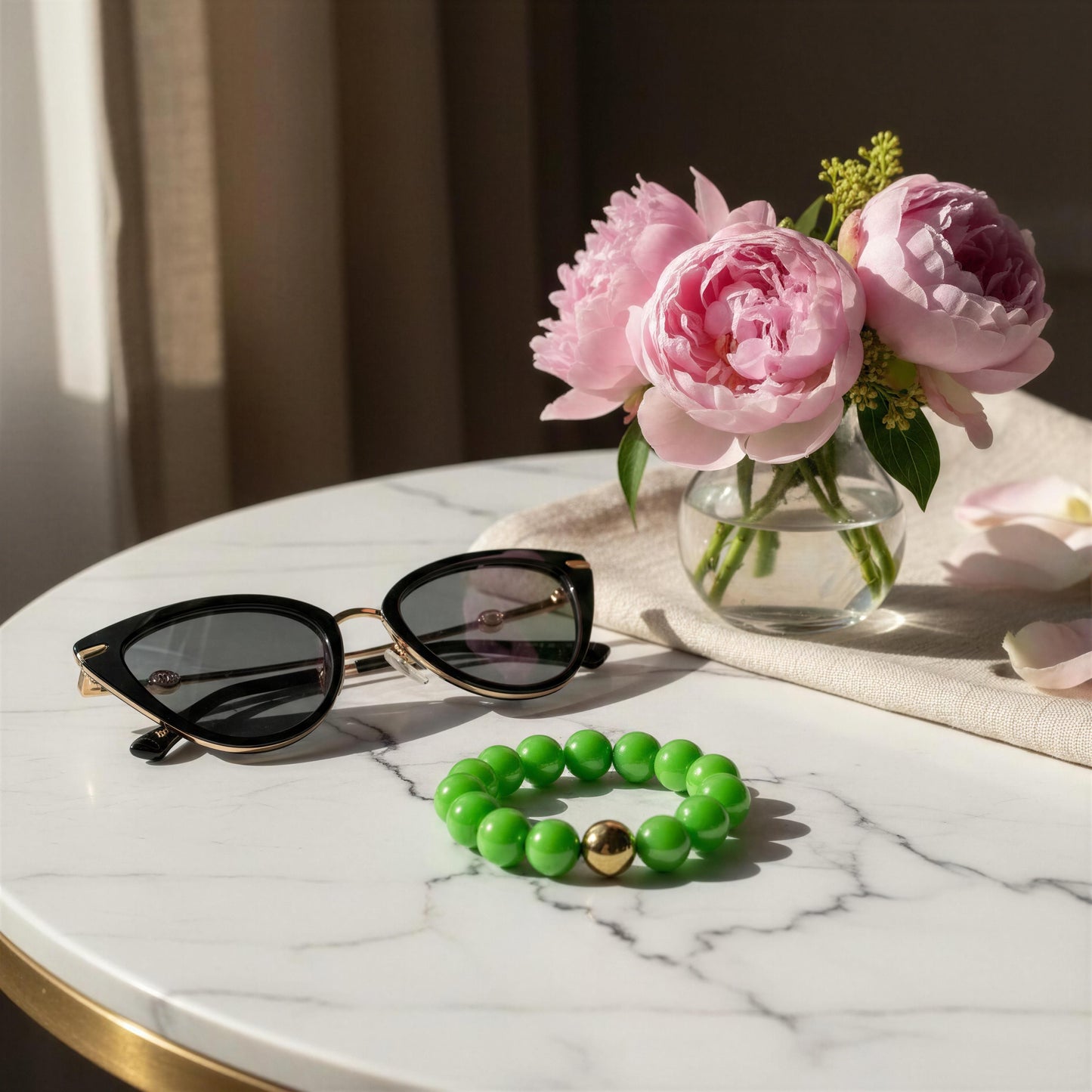 Sunglasses, the Green Apple Bracelet and pink flowers on a marble surface