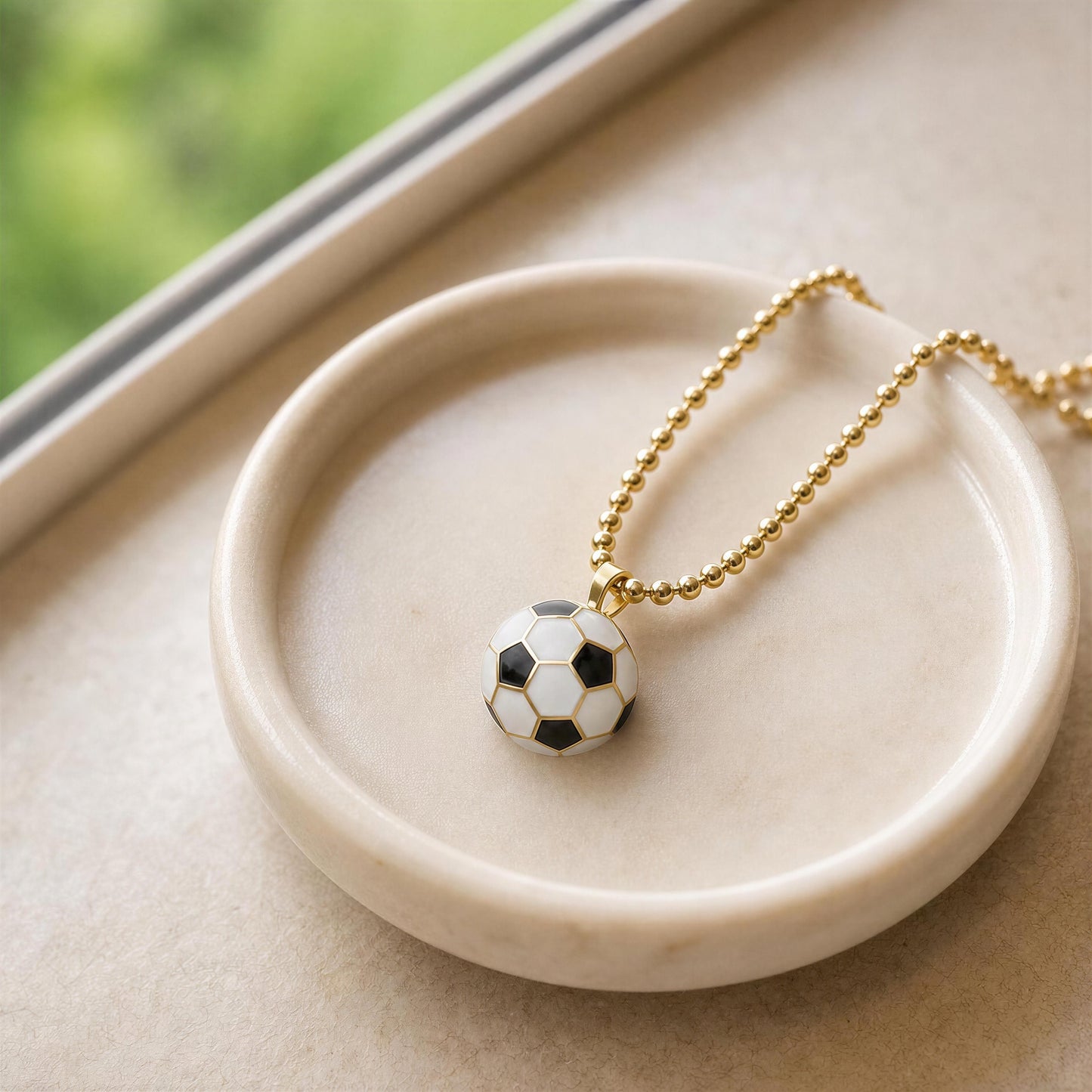 La Vittoria Charm Necklace with soccer ball pendant on a beige dish