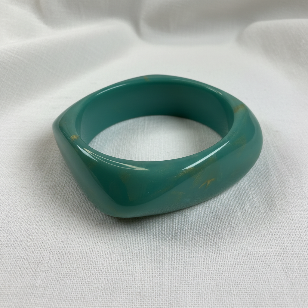 Green Chica_Chica_Jewelry-_Ocean_Twist_Bangle on a white fabric background