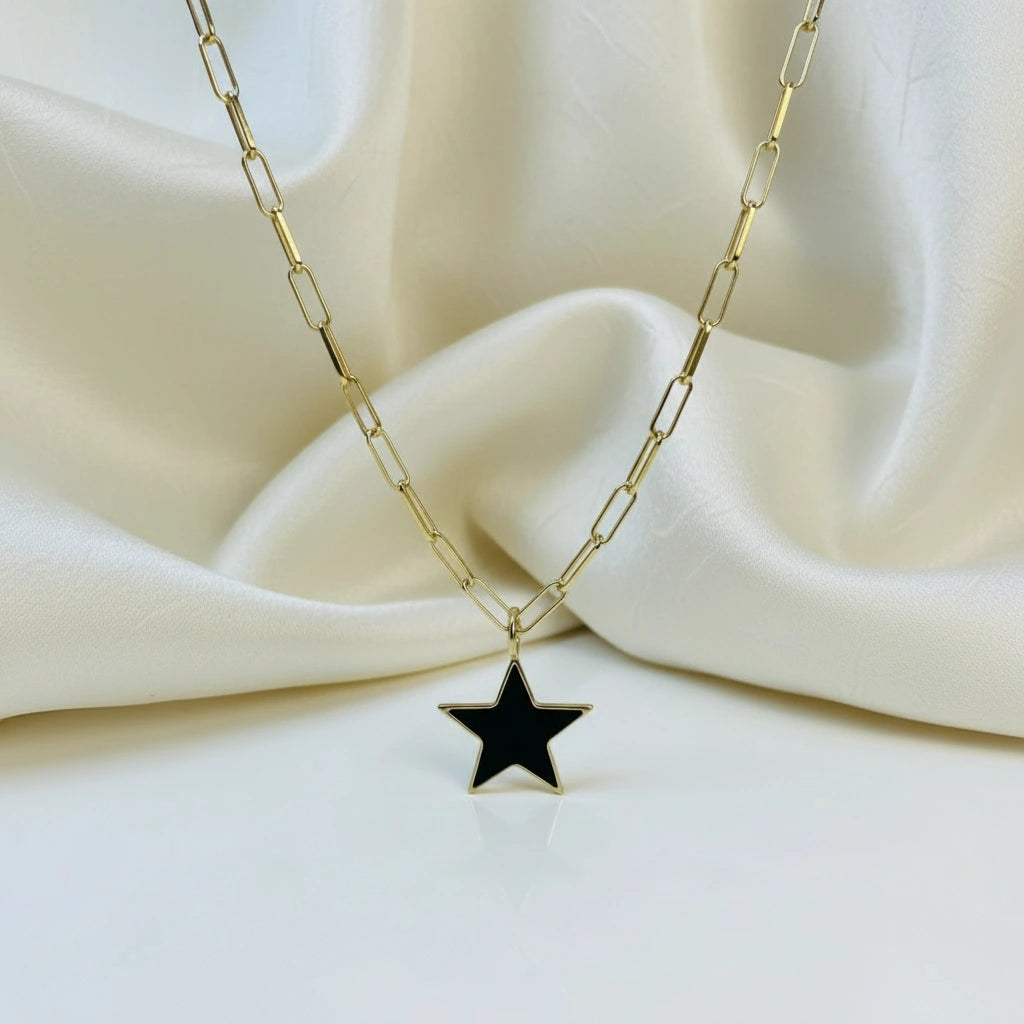 Gold chain necklace- Radiant Noir Star Necklace- with a black star pendant on a white fabric background