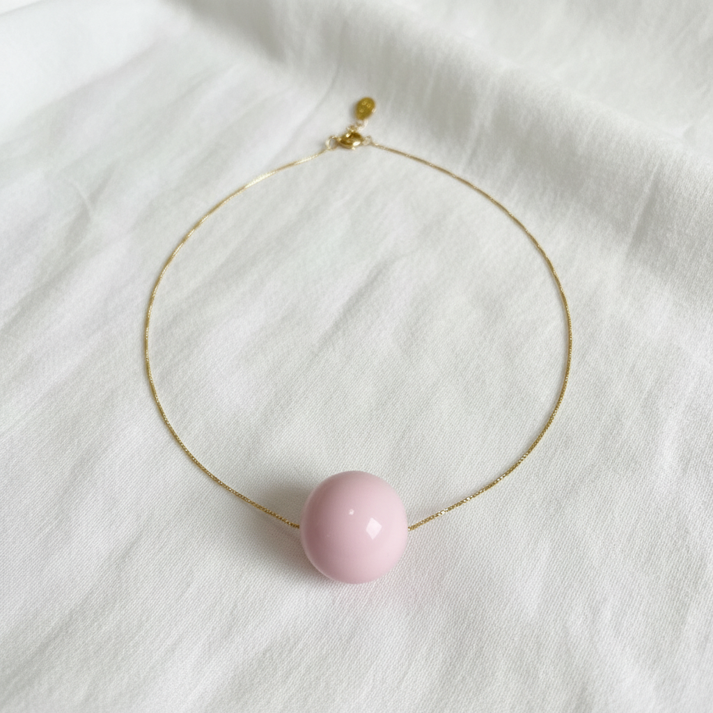 Rosé Sphere Statement Necklace with a pink bead on a white fabric background