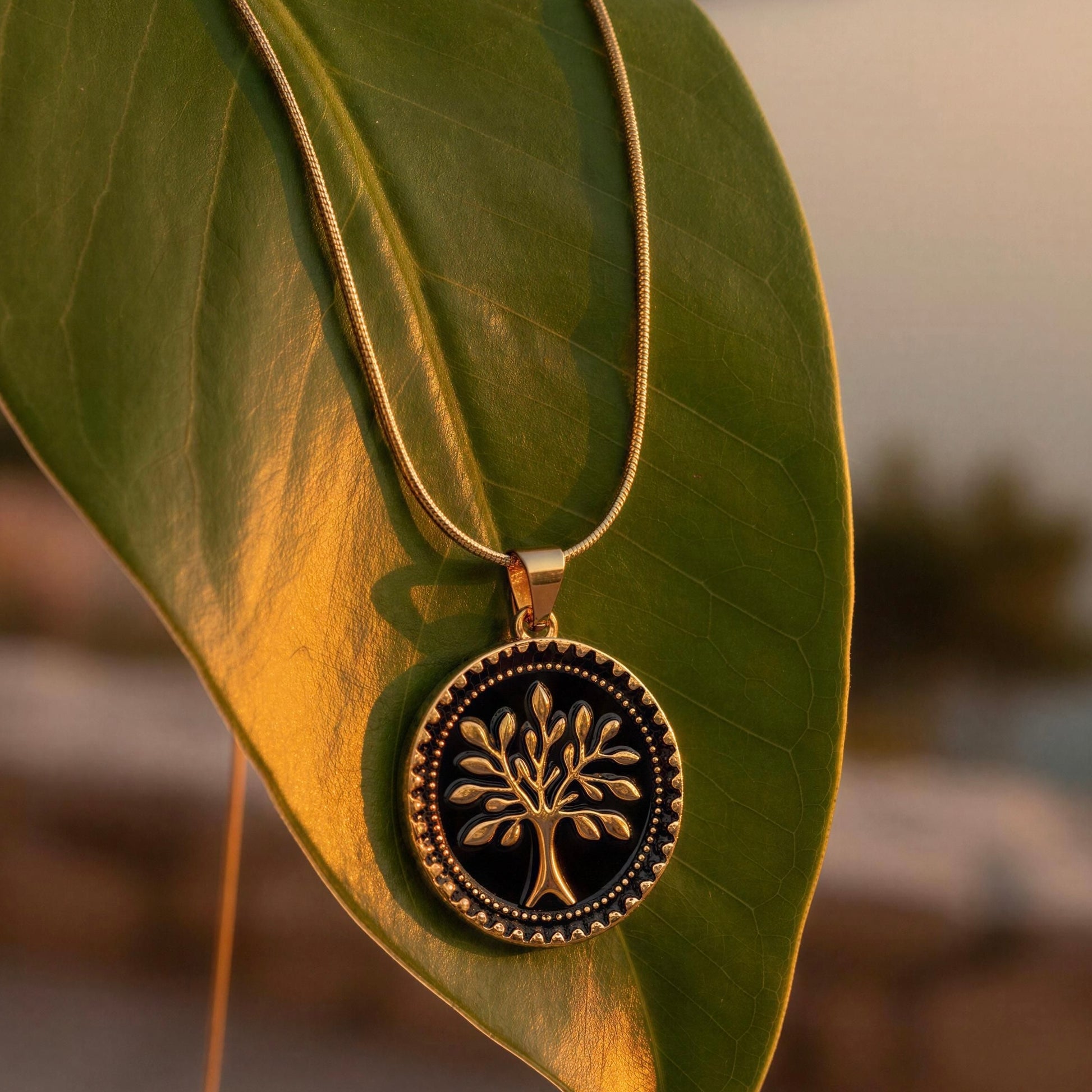 Gold necklace with a tree pendant on a green leaf