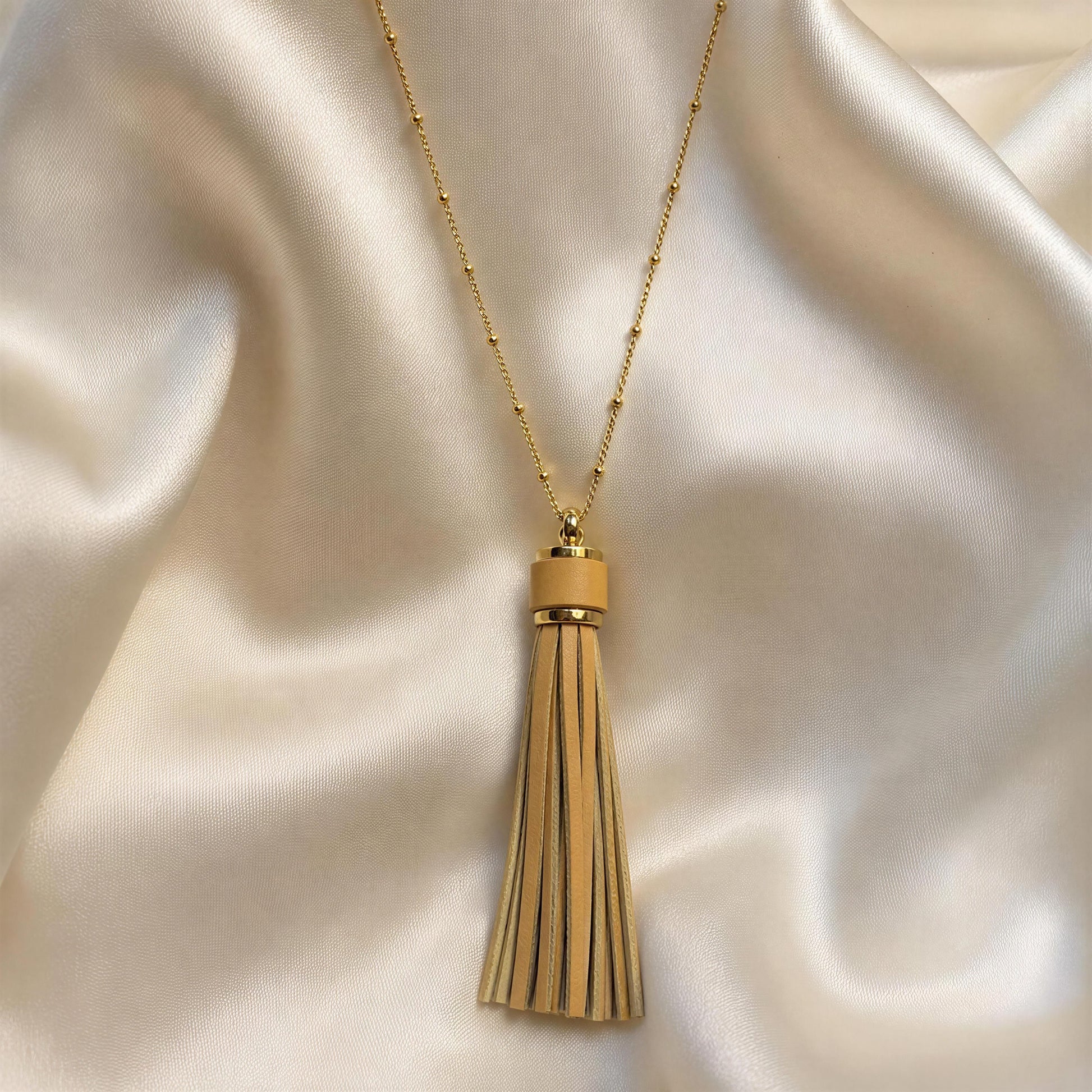 The Frangia Avorio Necklace, displayed on draped cream satin fabric.