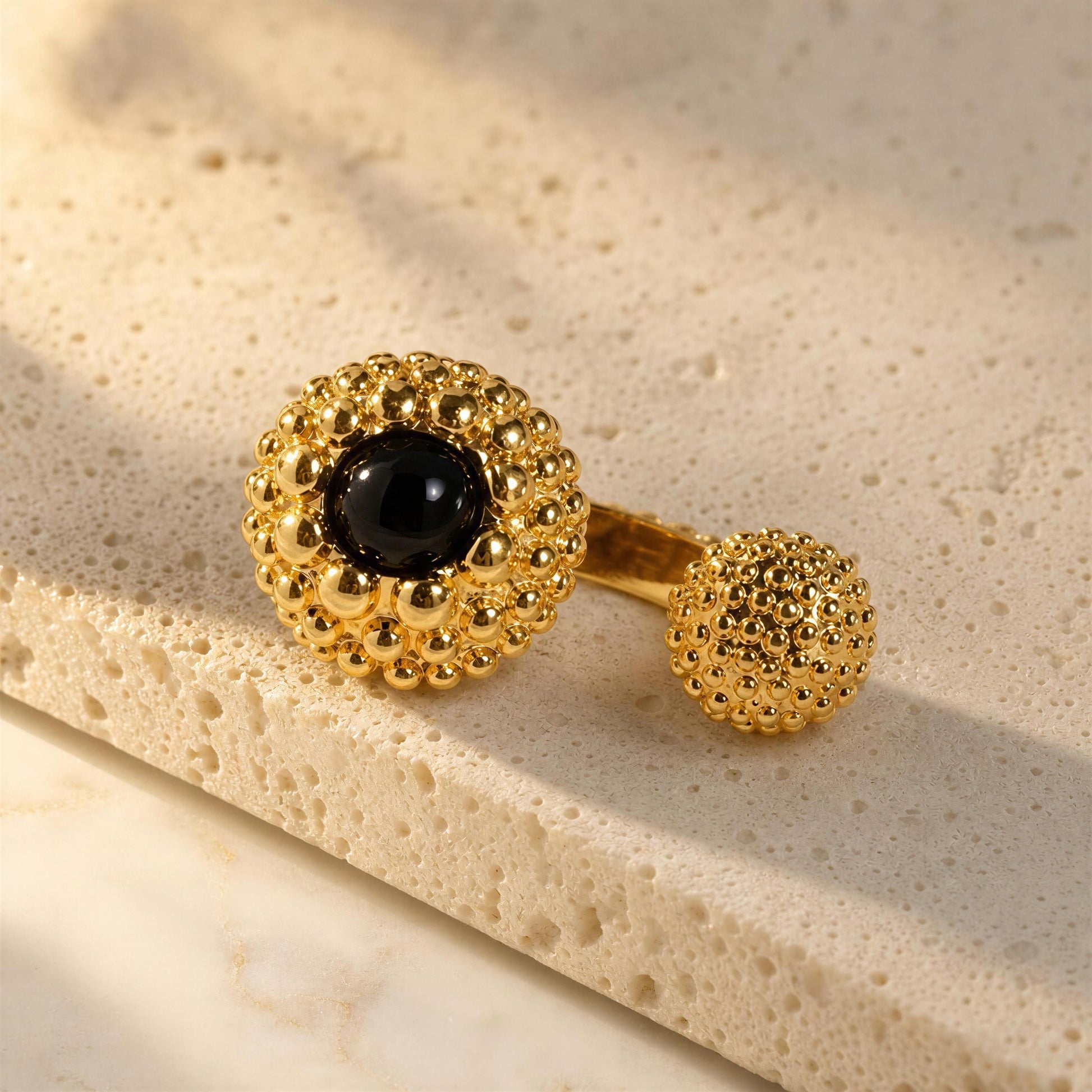 Chica Chica Jewelry,  Nero Ring,  displayed on a textured beige stone surface.
