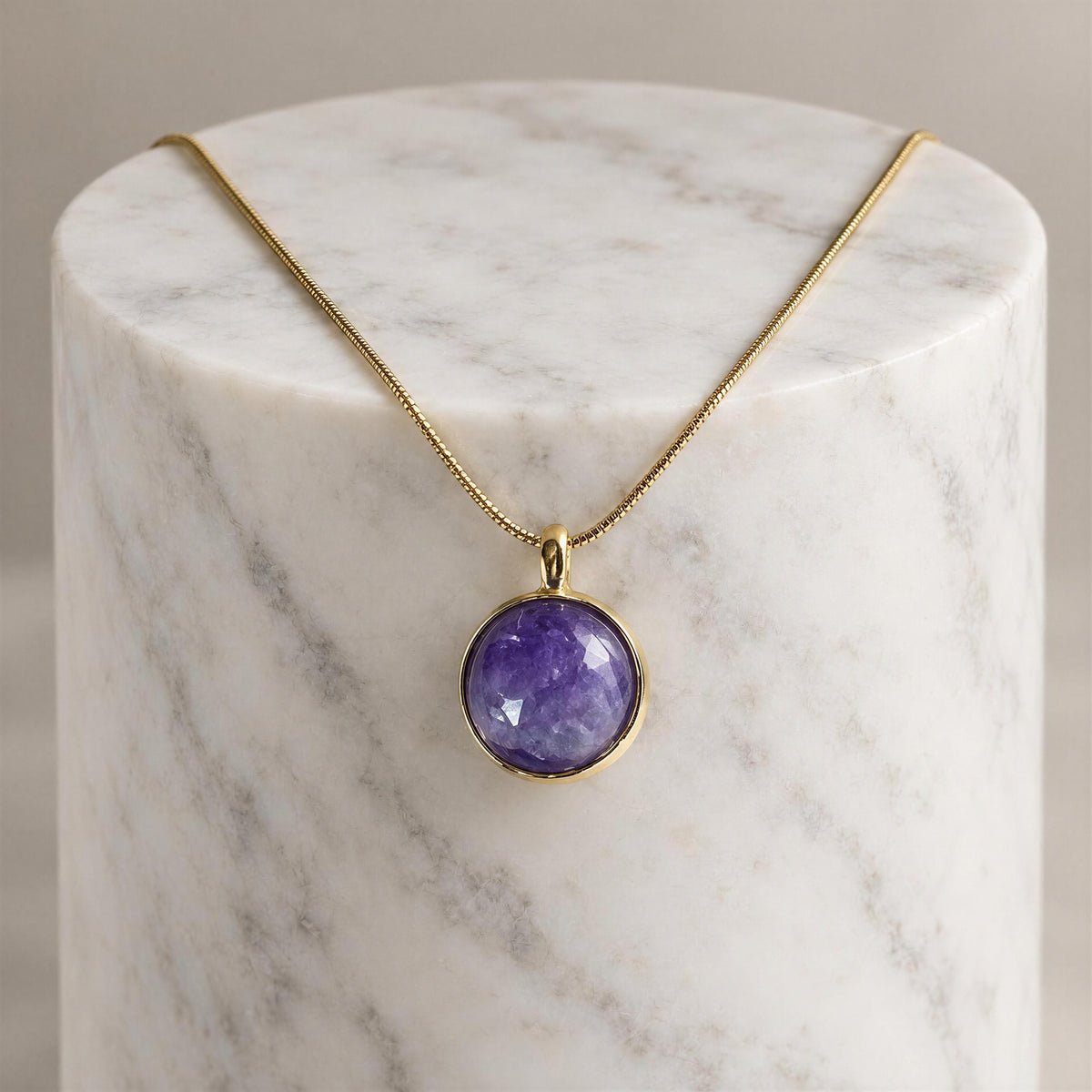 The Chica Chica Jewelry Lavanda Necklace draped from a top marble white pedestal. 
 