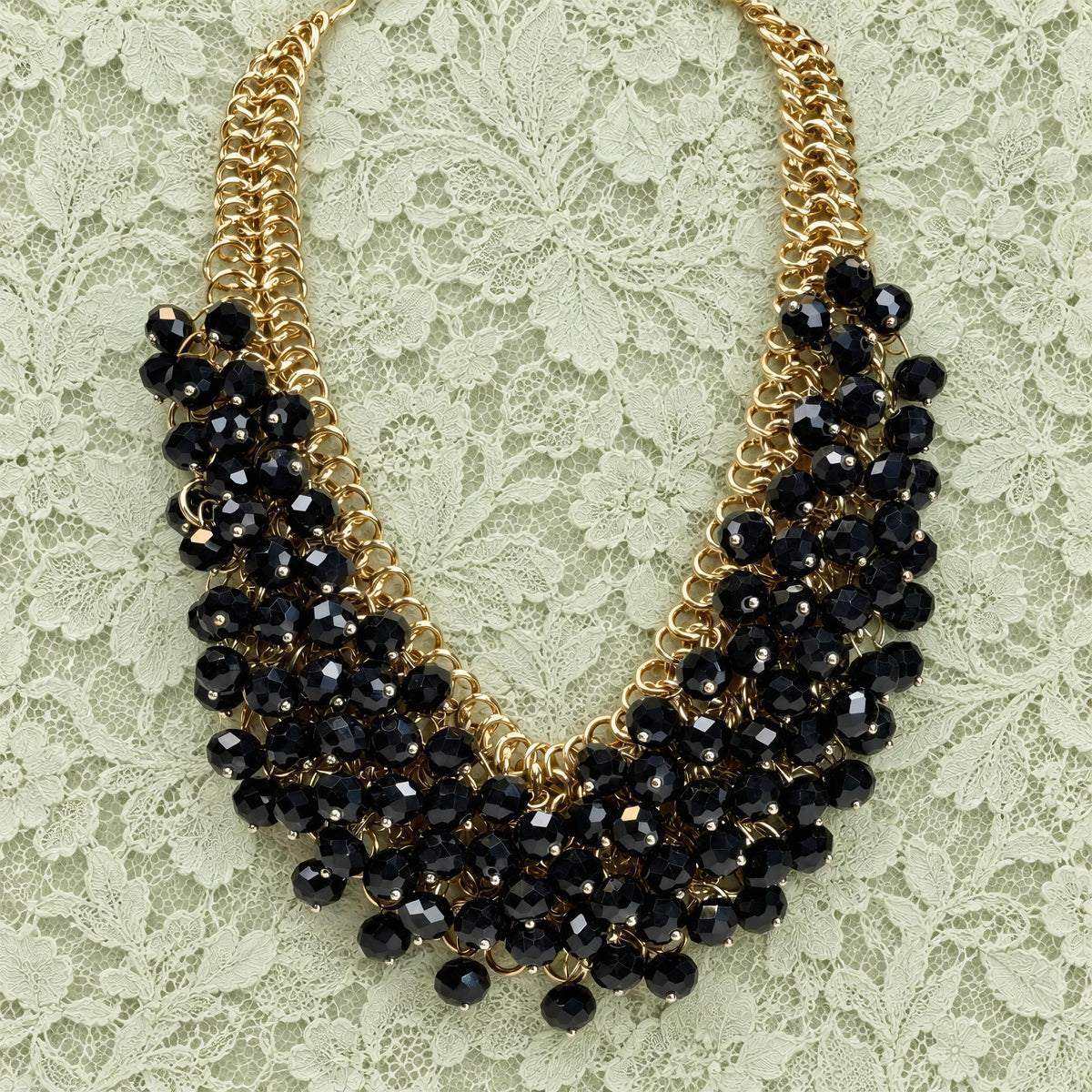 The Chica Chica Jewelry  Marcella Necklace, against a light green pistachio color lace fabric.