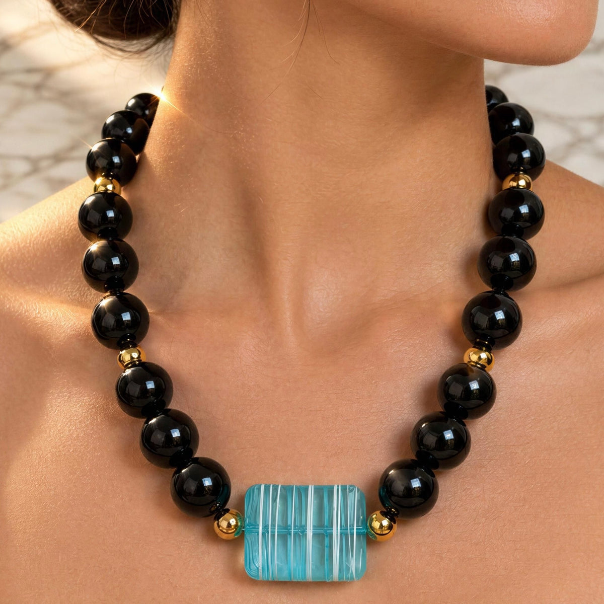 Close-up of Mara Necklace with striped aquamarine acrylic centerpiece and glossy black beads from Chica Chica Jewelry 