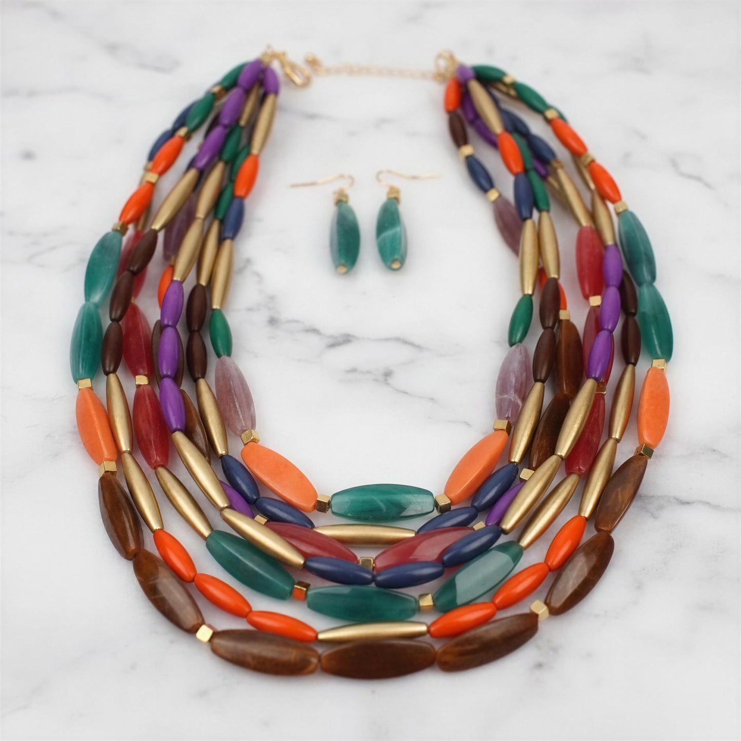 The Riviera Mosaic Necklace Set from Chica Chica Jewelry on a marble surface