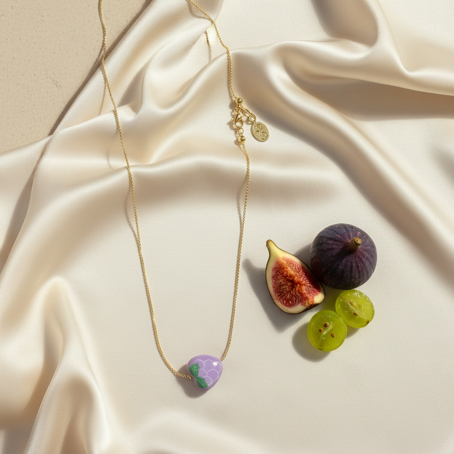 Tutti Frutti grape necklace displayed on soft fabric with fruit styling accents