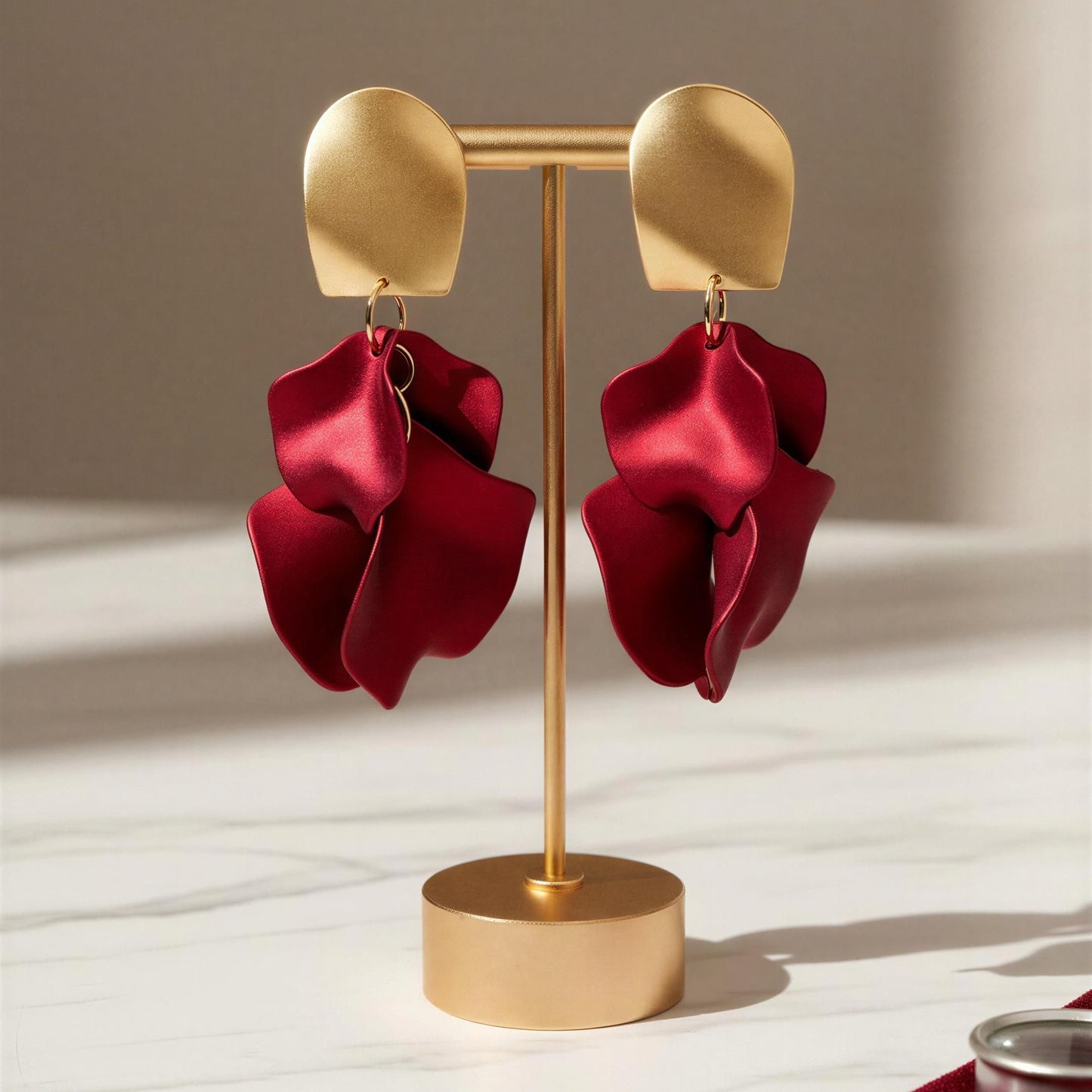 Red earrings on a gold earring stand with a neutral background
