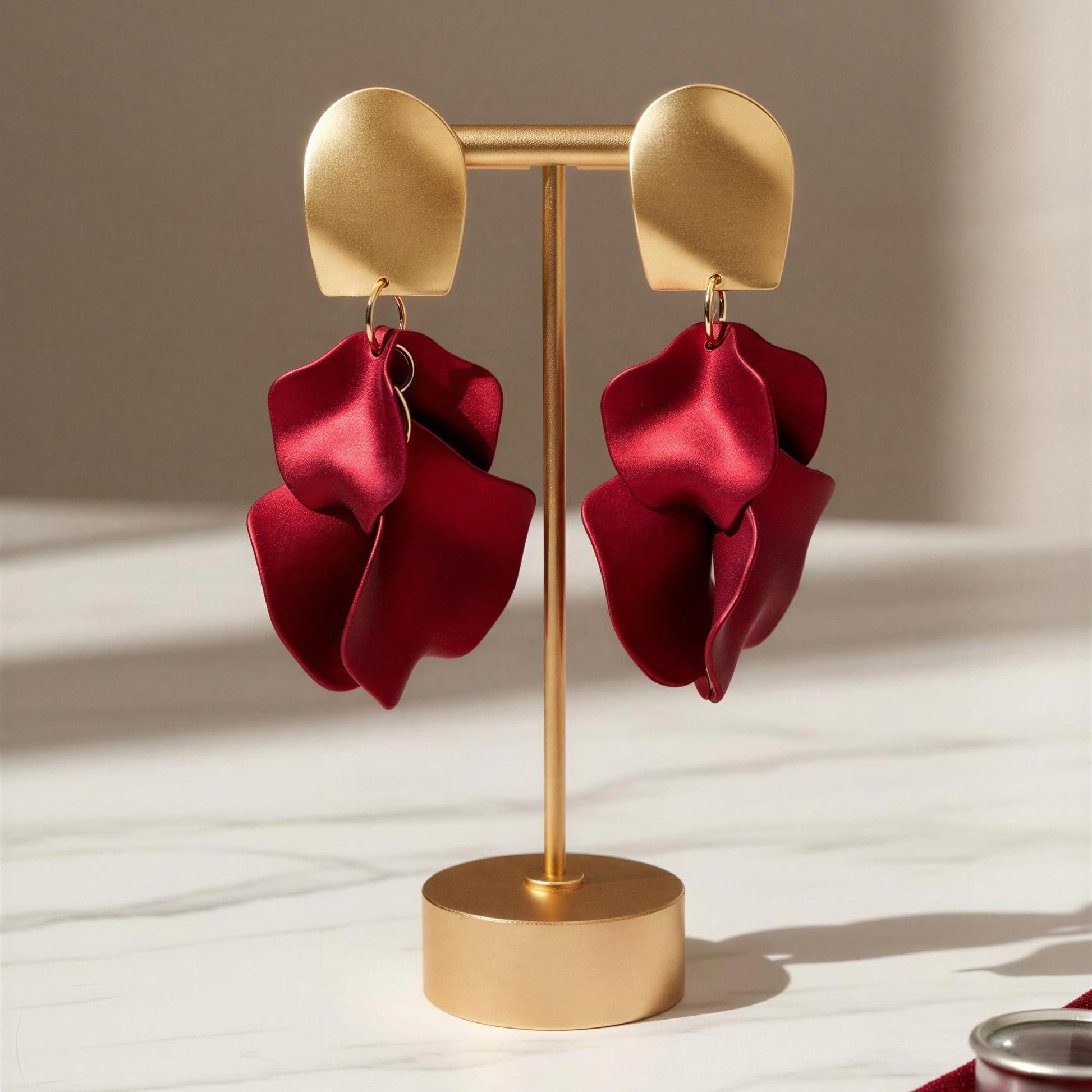 Red earrings on a gold earring stand with a neutral background
