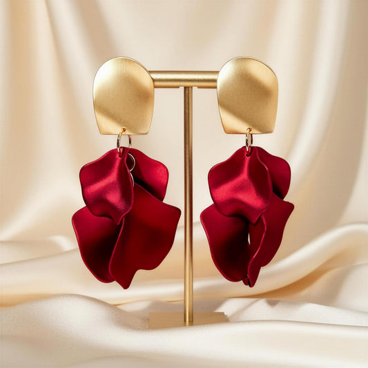 The Crimson Bloom Earrings with red satin bows on a beige fabric background