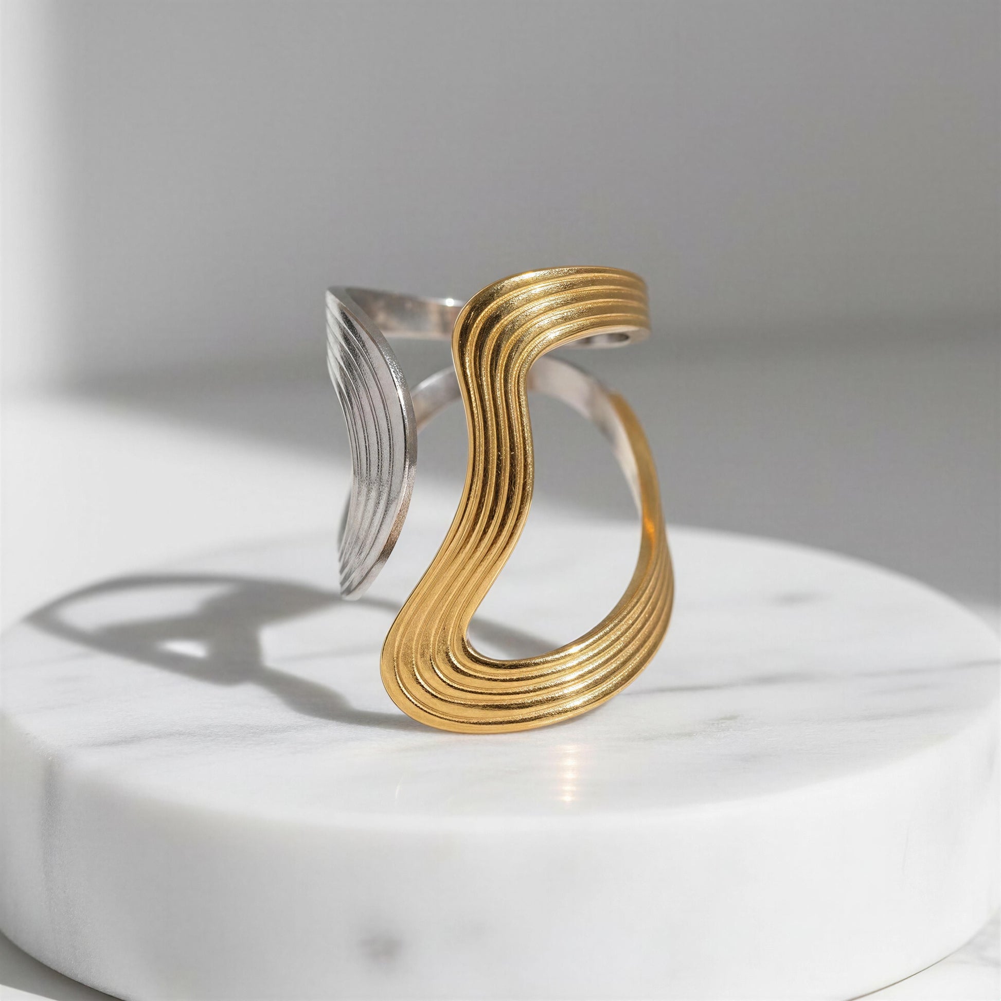 Gold and silver ring on a white platform with a light gray background