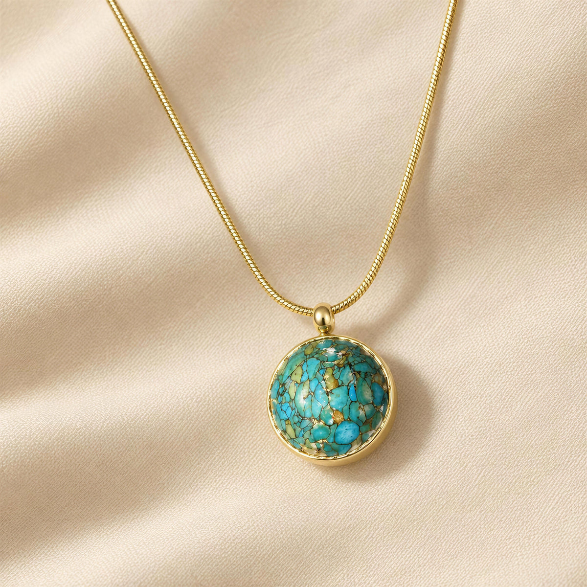 Derya round turquoise pendant necklace with delicate gold-tone chain arranged on soft ivory linen fabric.