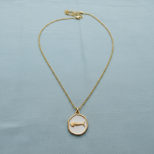 Driftmark Fish Necklace on a light blue fabric background