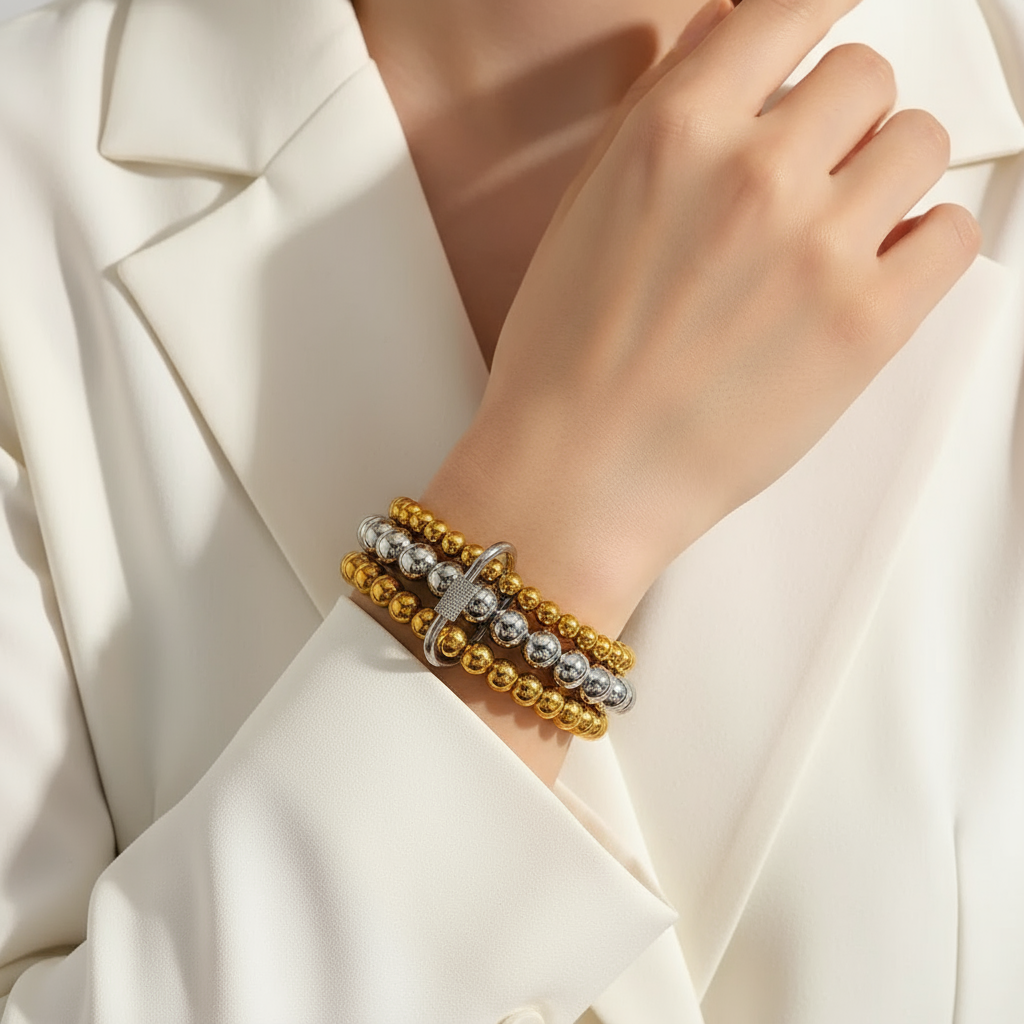 Gold and silver bracelet on a person's wrist with a white background