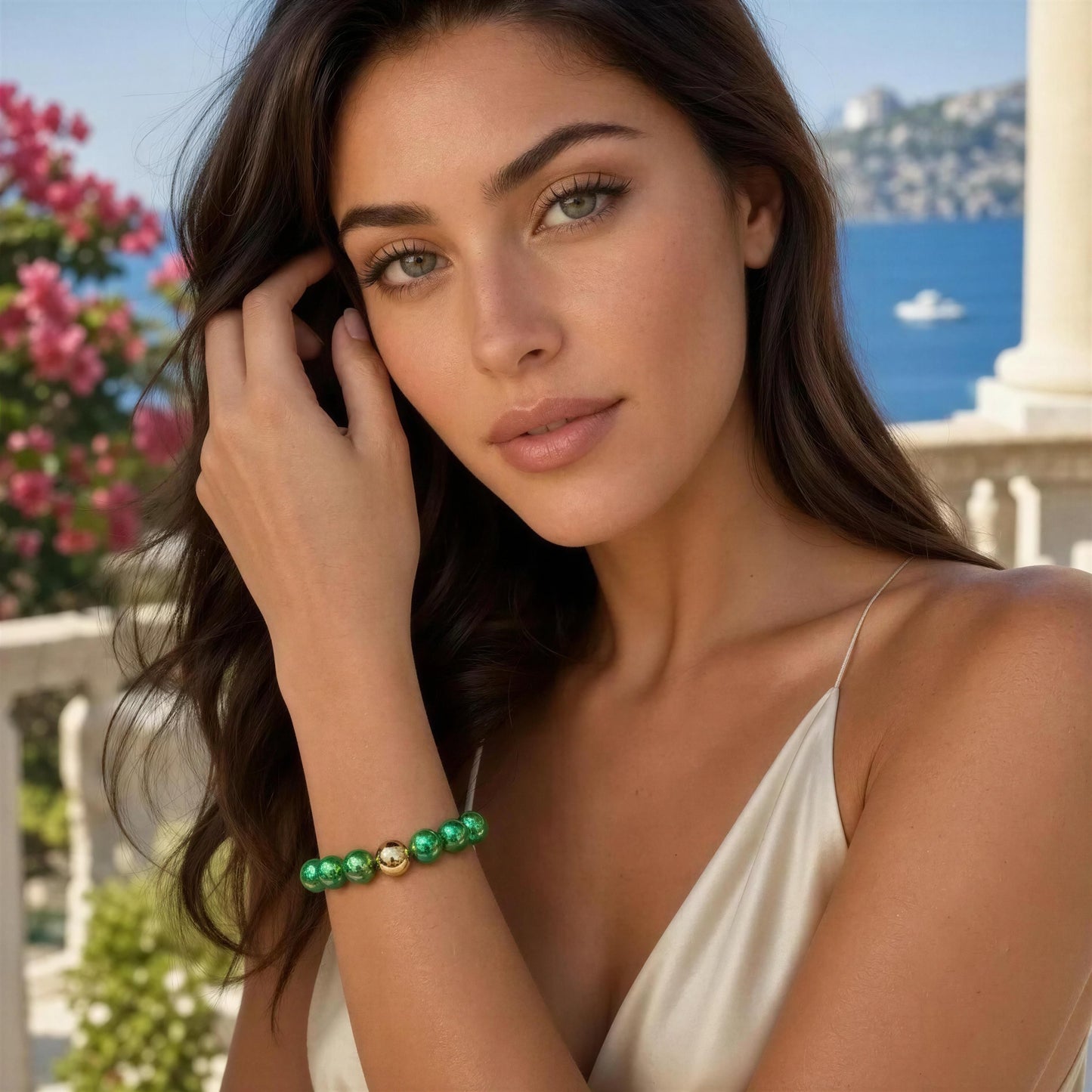 Woman wearing the Emerald Glow Bracelet on a balcony with a scenic background