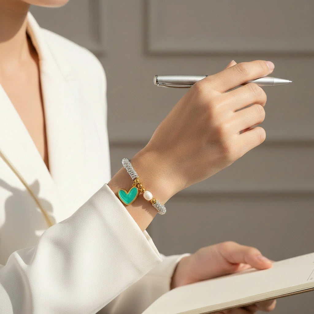 Person holding a pen with a decorative bracelet on a neutral background