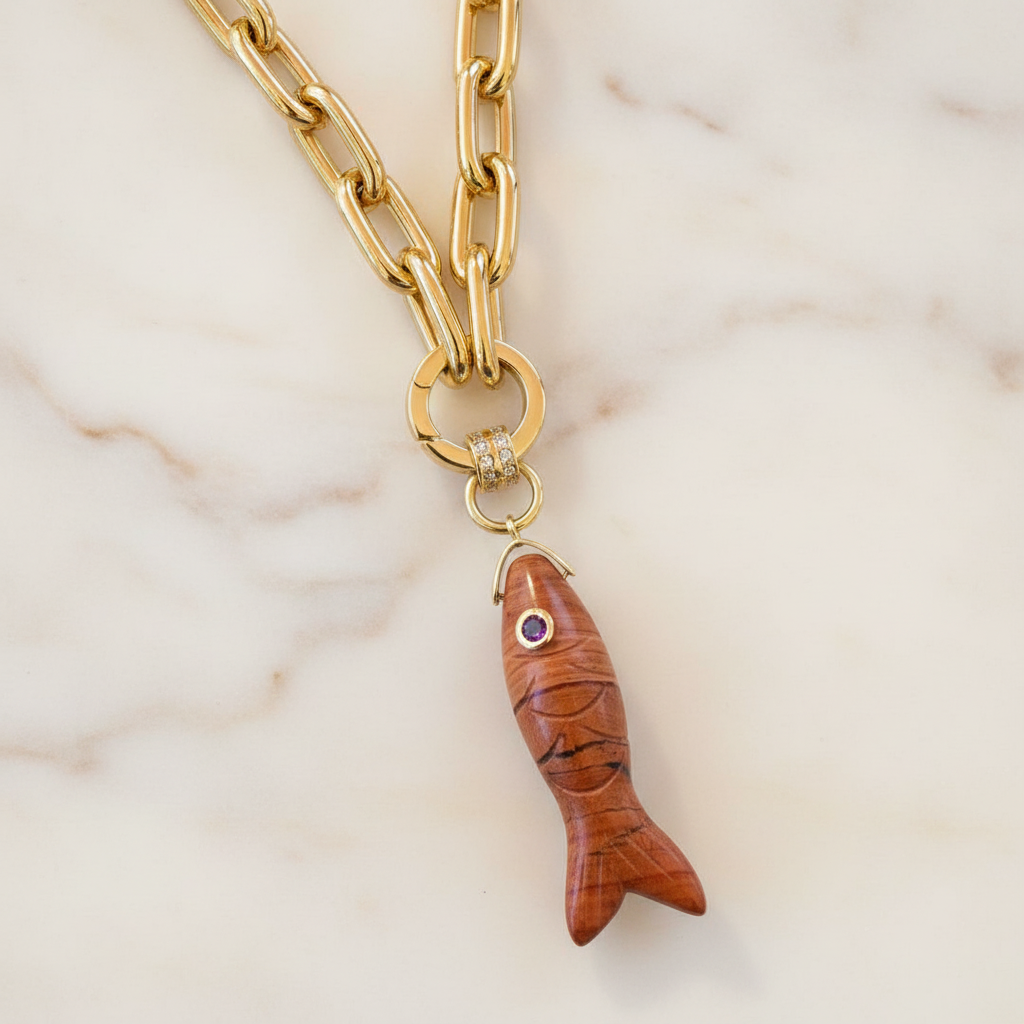 The Espresso Fish Necklace with a natural gemstone  fish pendant on a marble background