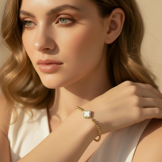 Woman wearing a gold bracelet with a clear stone on a beige background