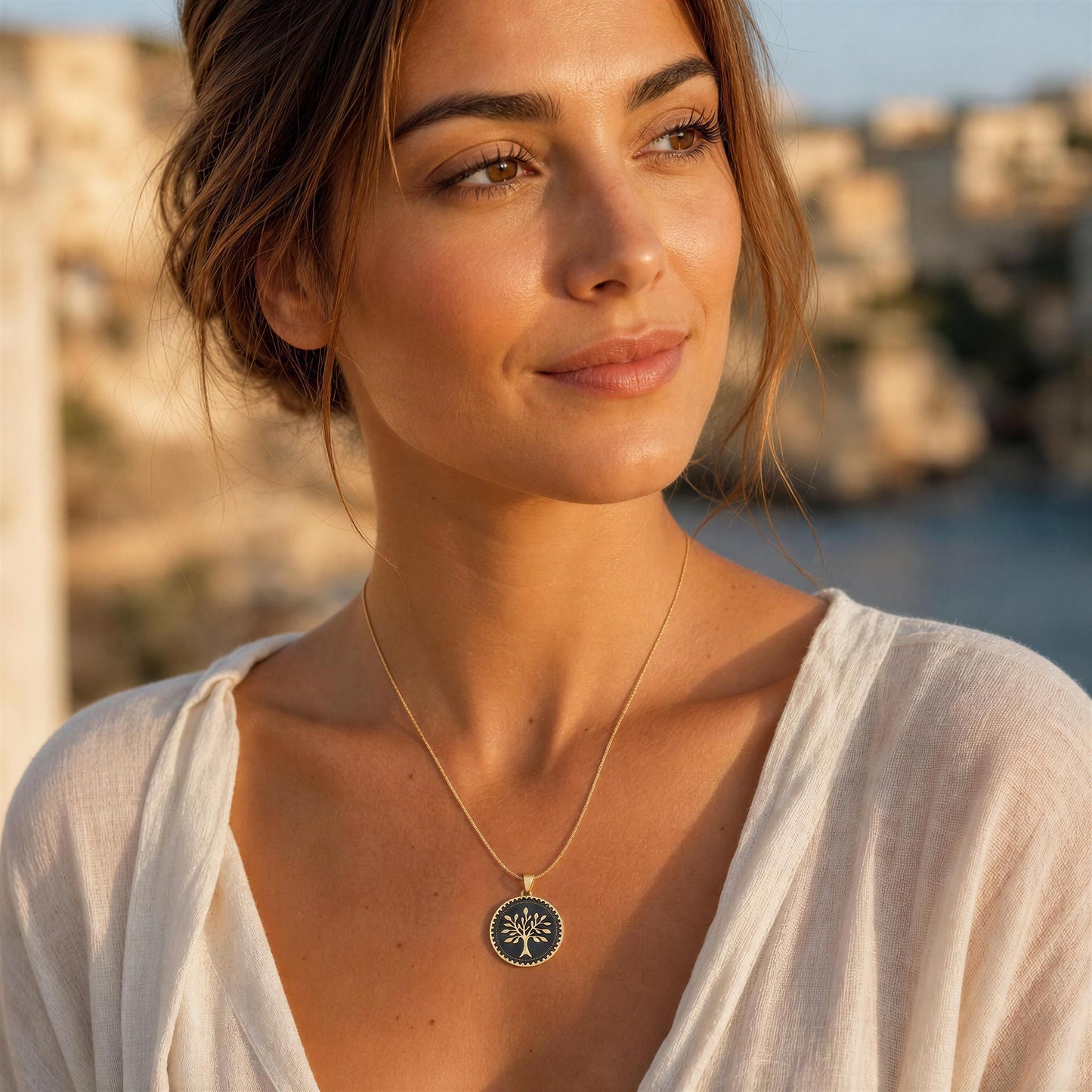 Woman wearing a necklace with a tree of life pendant in a scenic outdoor setting.