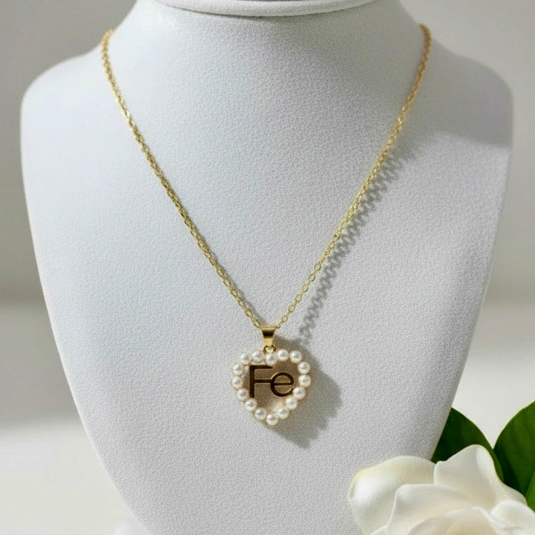 Chica Chica Jewelry - Gold necklace with a heart-shaped pendant on a white bust, accompanied by a white gardenia.