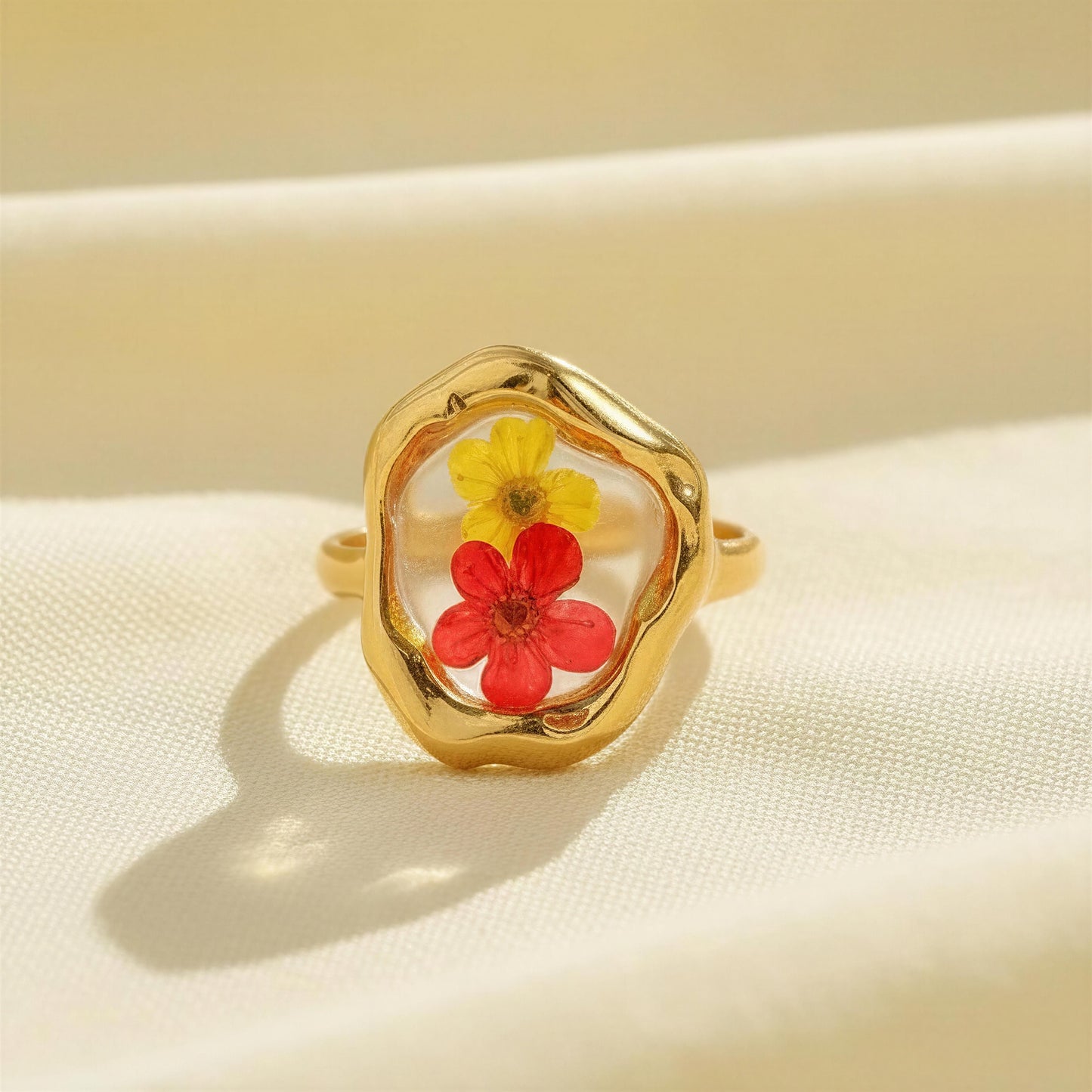 Gold ring with red and yellow flowers on a beige background