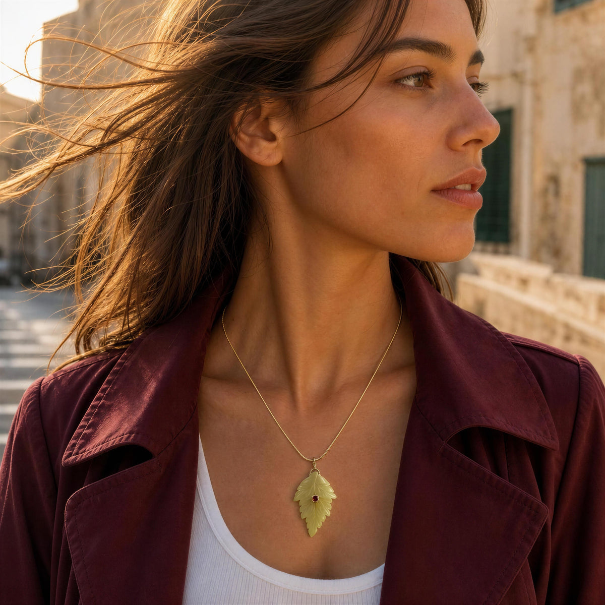 Model wearing a burgundy trench coat by Mediterranean scenery and the Fiorella Necklace from Chica Chica Jewelry. 