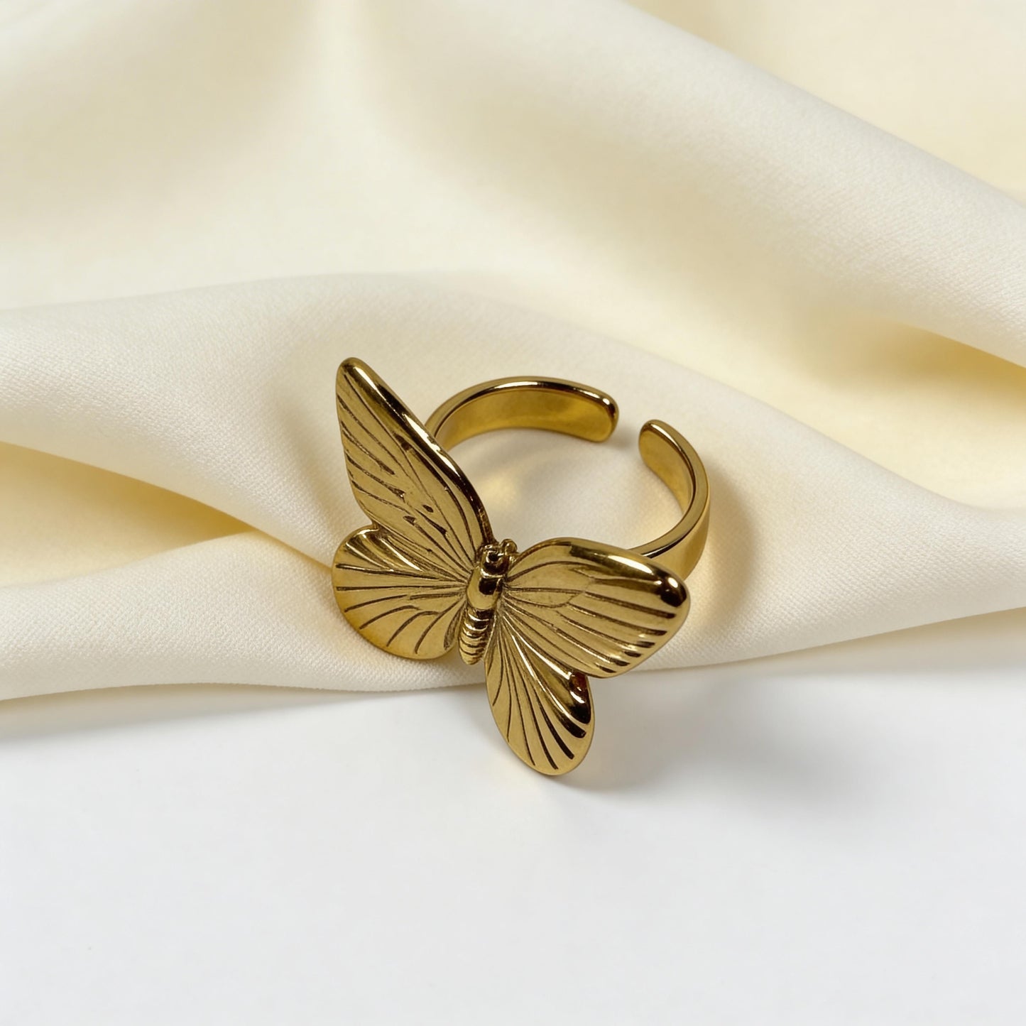 Gold butterfly-shaped ring on a soft fabric background