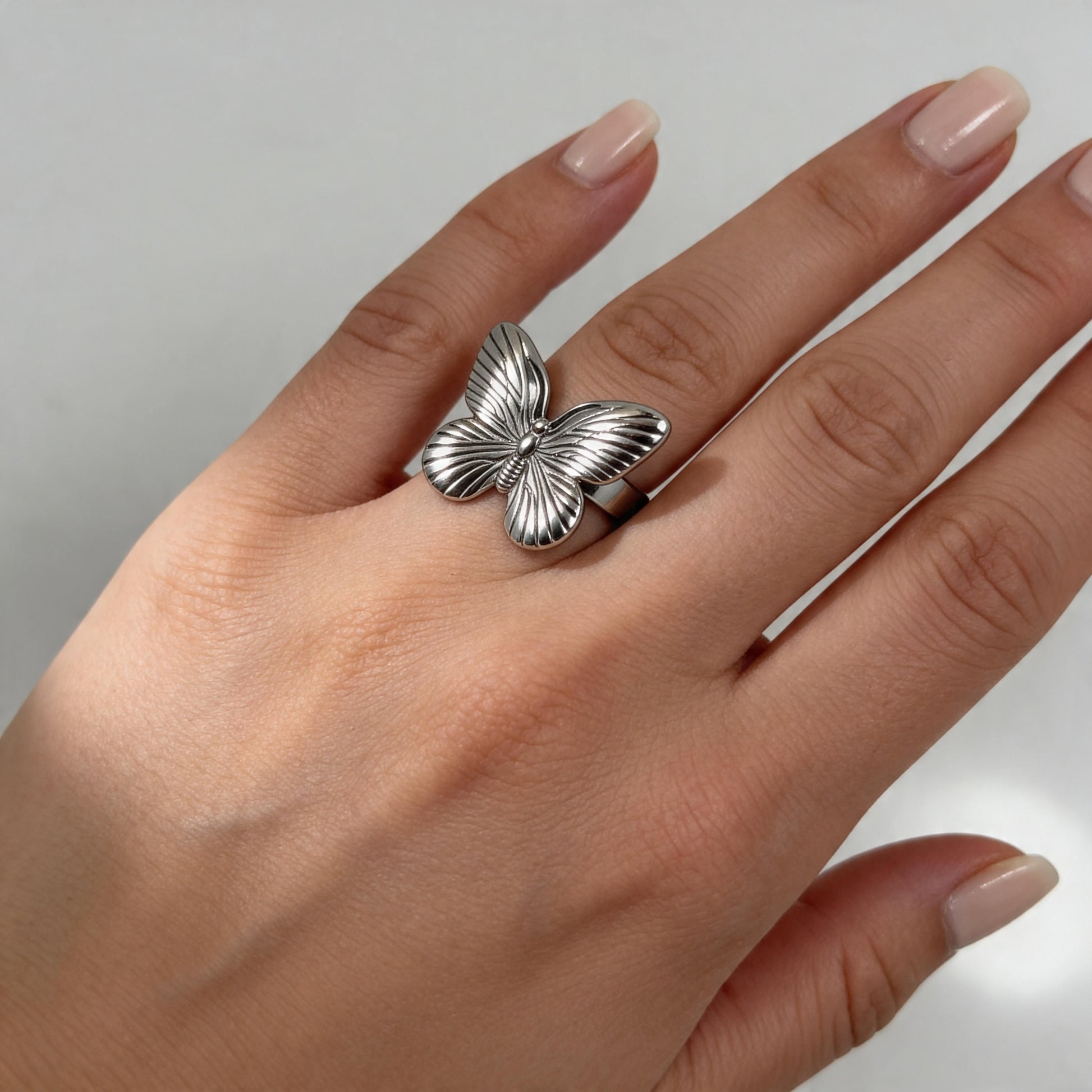 The Forever Flutter Ring – Silver on  a person's finger against a neutral background
