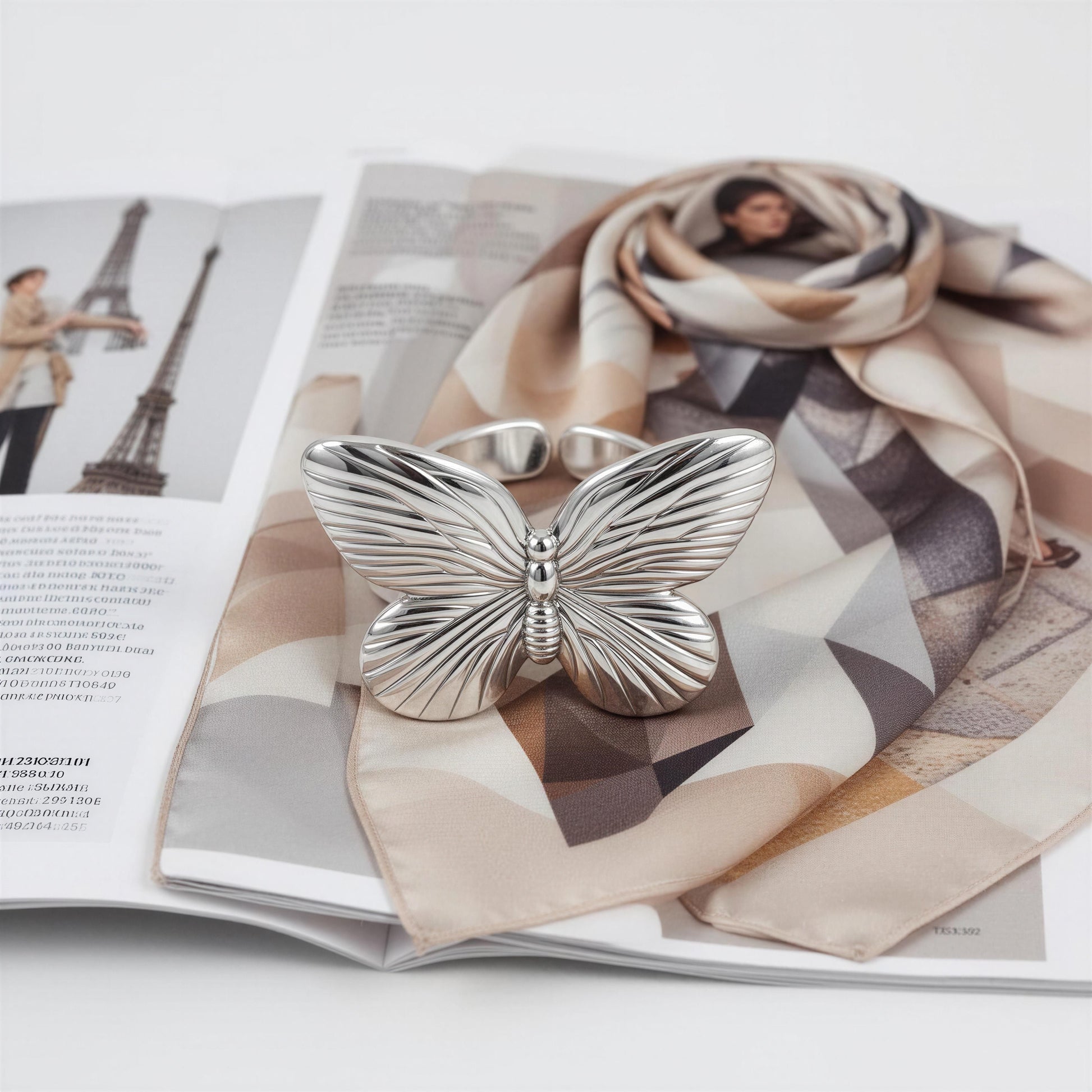 The Forever Flutter Ring – Silver on a patterned scarf with a magazine in the background