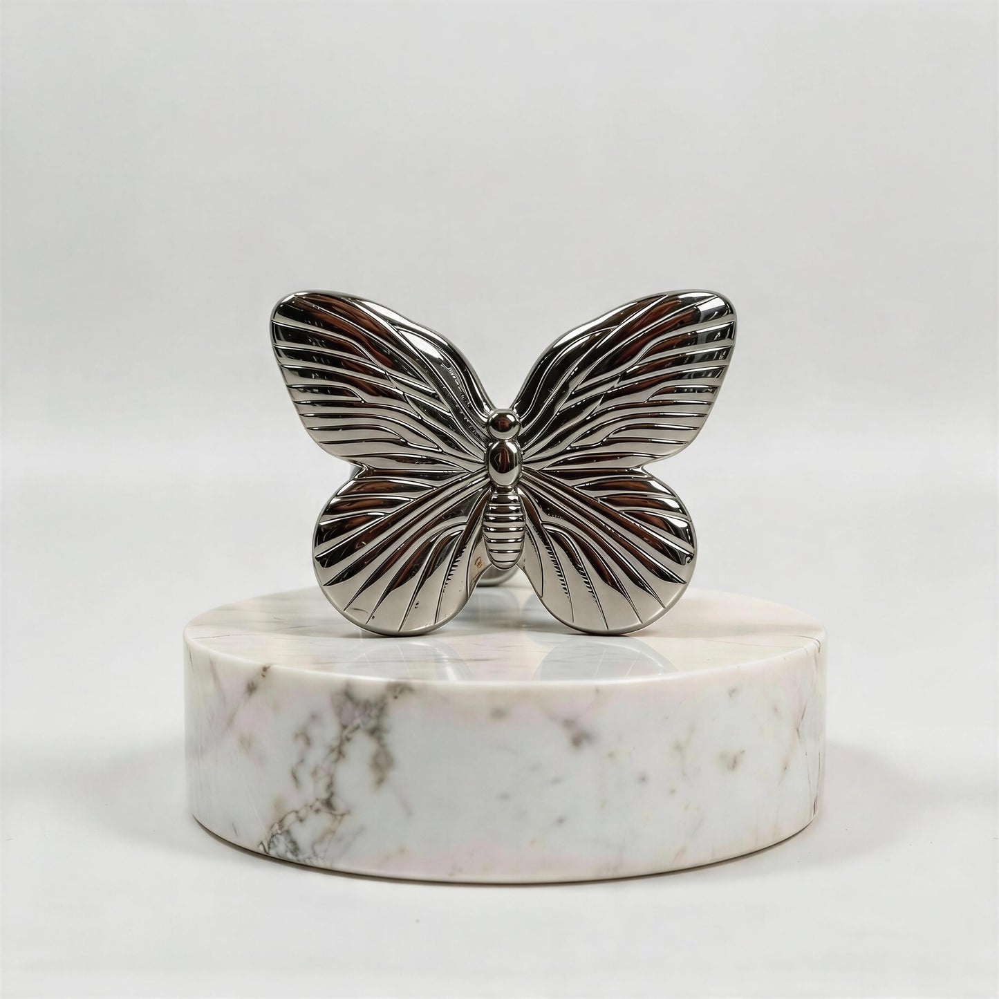 Silver butterfly ring on a marble base against a white background