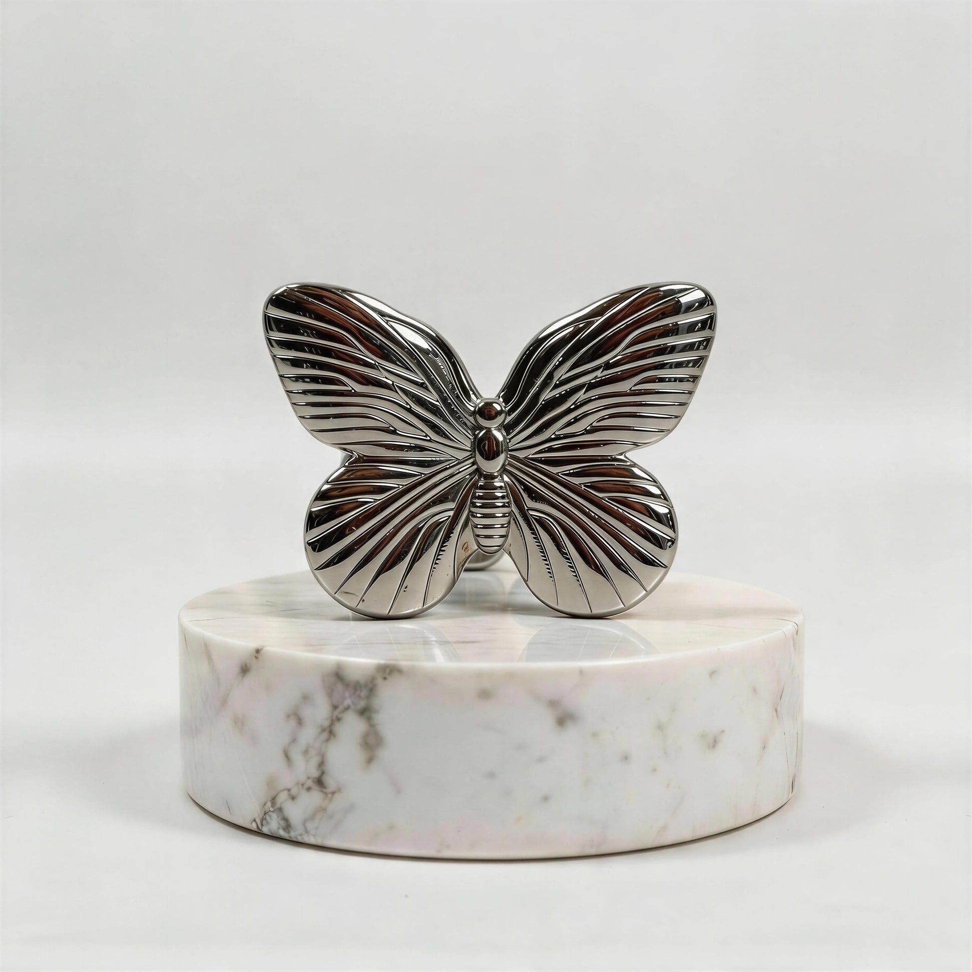 Silver butterfly ring on a marble base against a white background