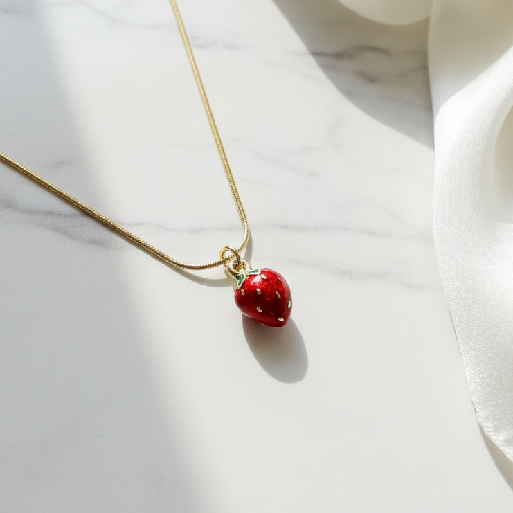 Fragola Charm Necklace with a red strawberry pendant on a marble surface