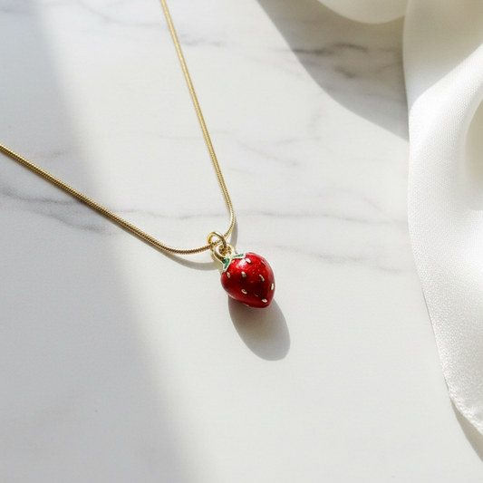 Fragola Charm Necklace with a red strawberry pendant on a marble surface