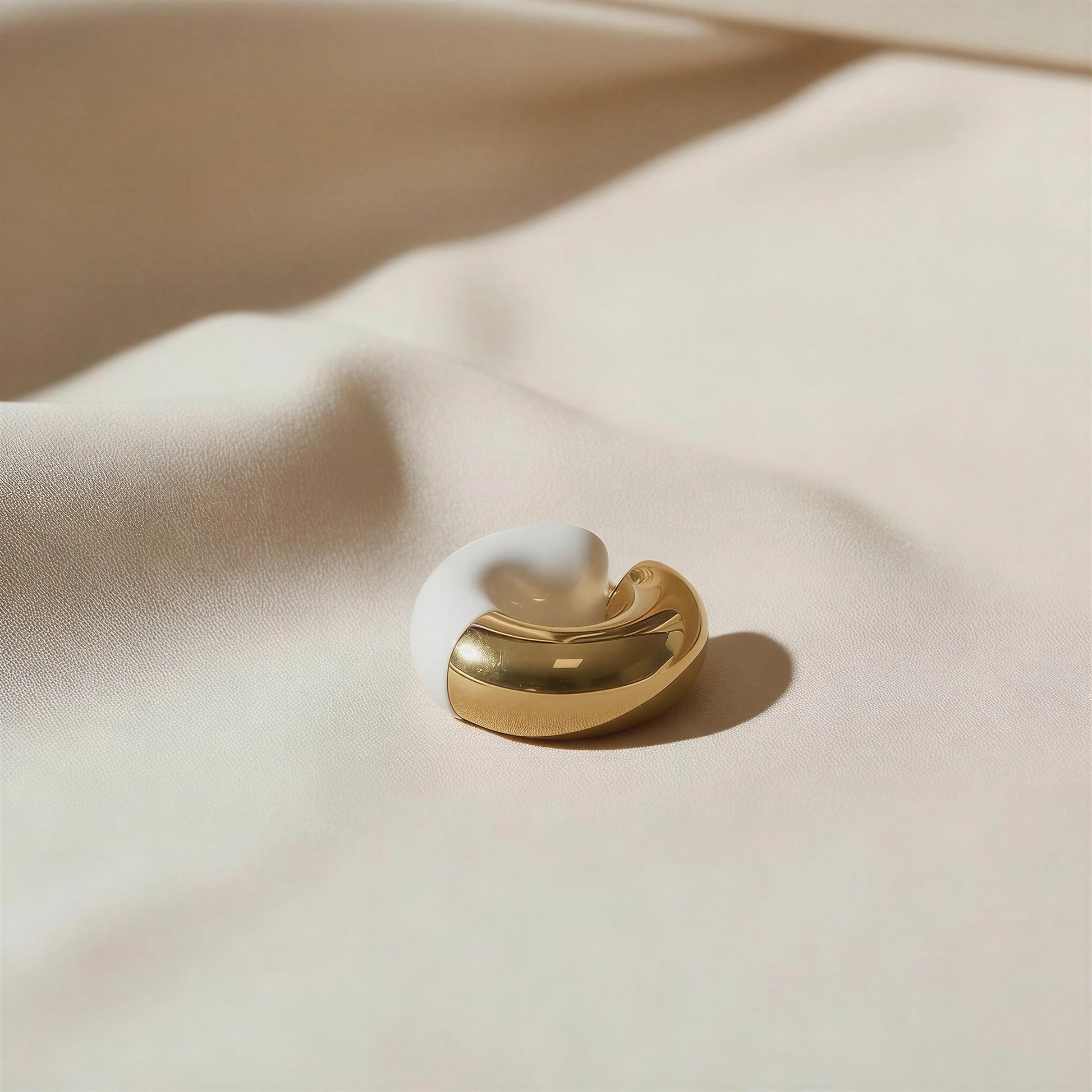 White and gold ear cuff on a beige fabric background