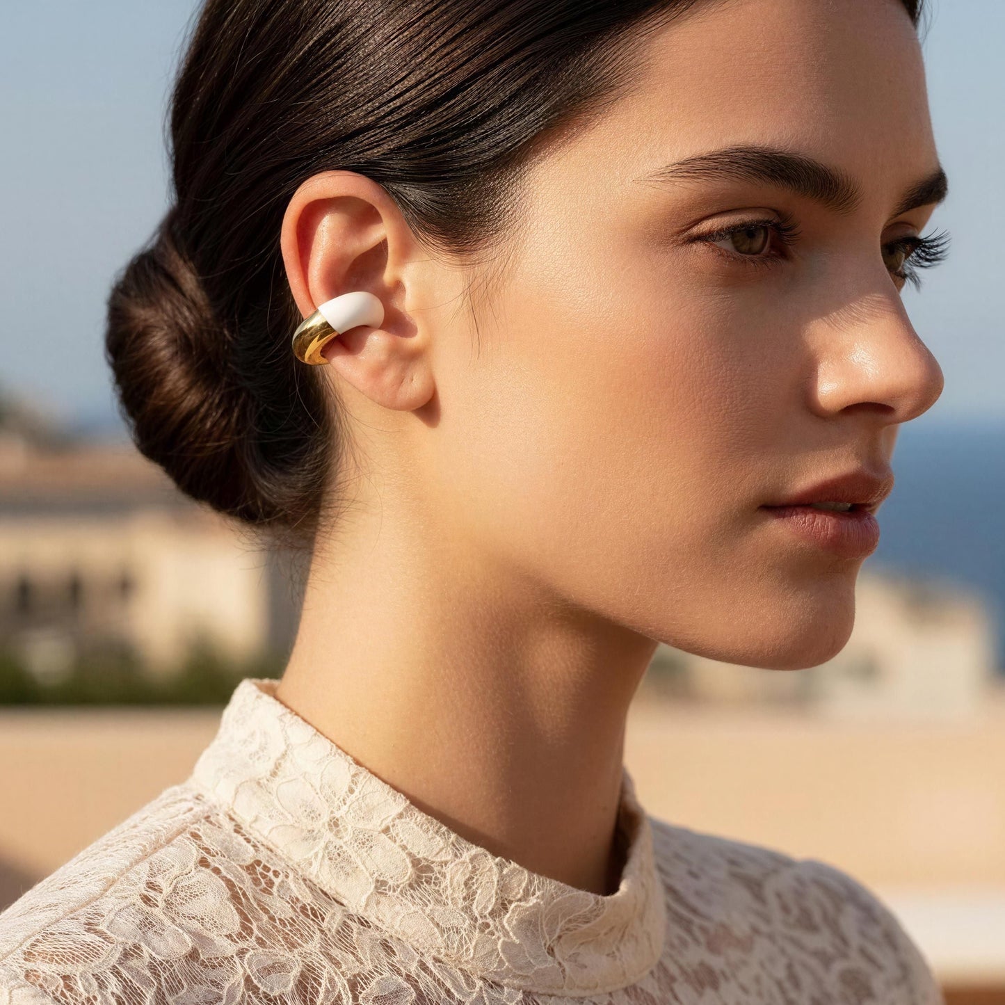 Woman wearing the Gatsby Arc Ear Cuff – Milky White with a scenic background