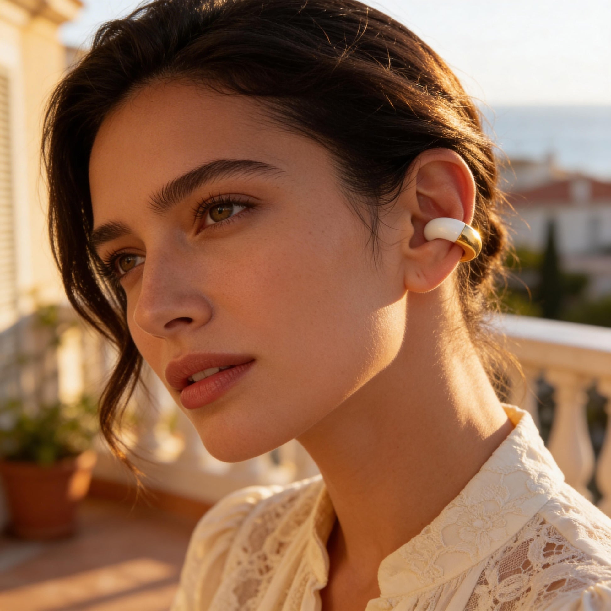 Woman wearing the Gatsby Arc Ear Cuff in Milky White a blurred outdoor background