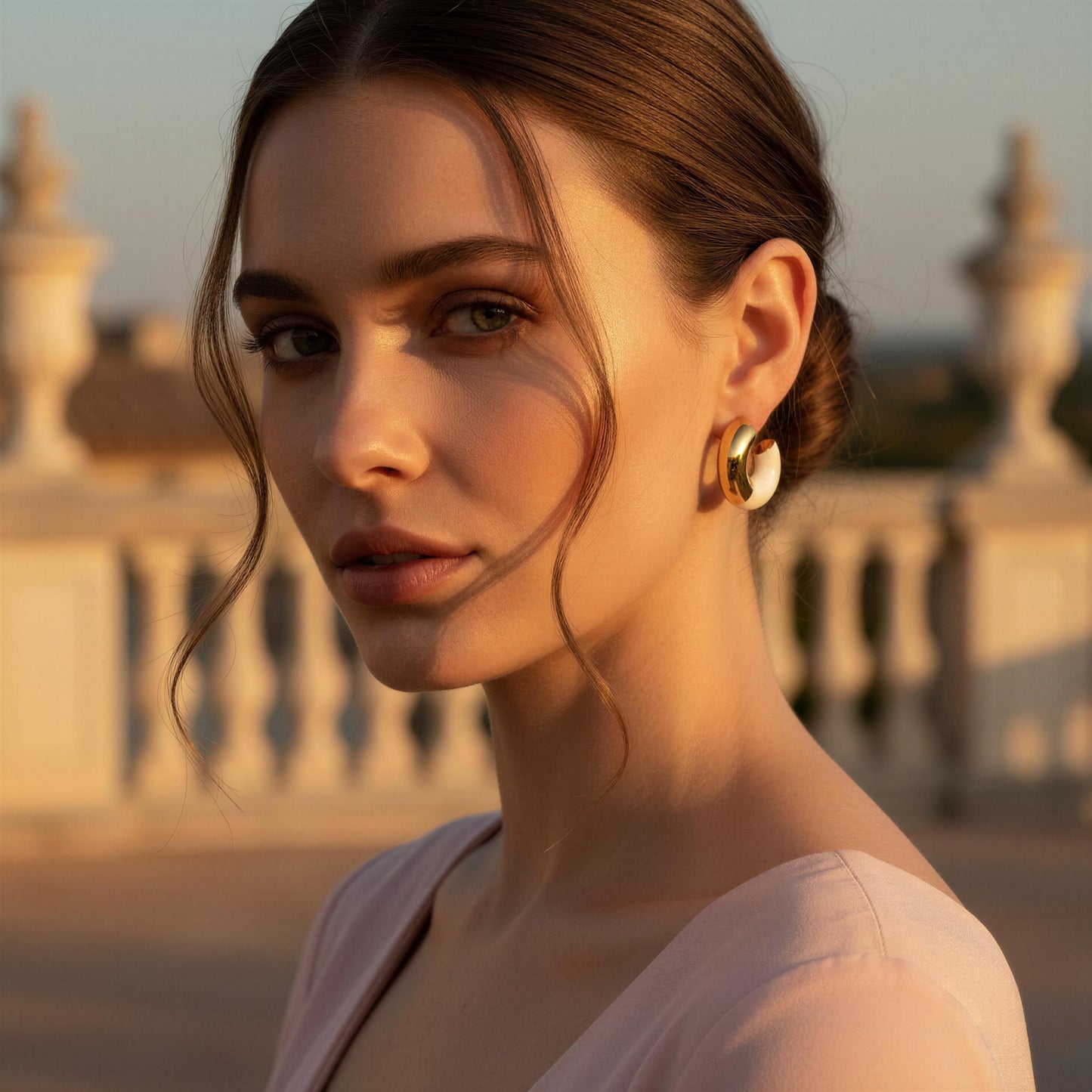 Woman with gold earrings in front of classical architecture