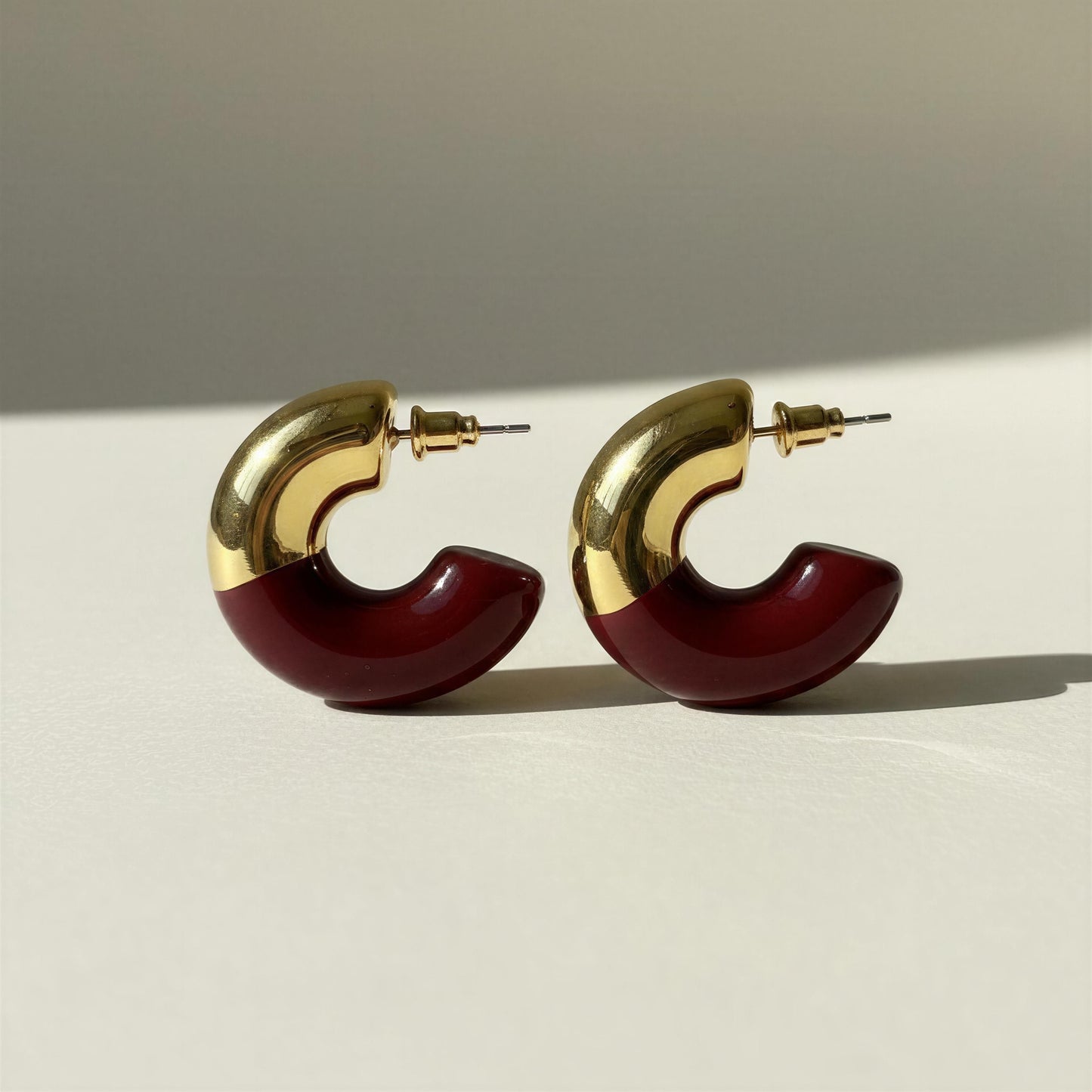 The Gatsby Arc Earrings in Merlot from Chica Chica Jewelry on a neutral light gray background.