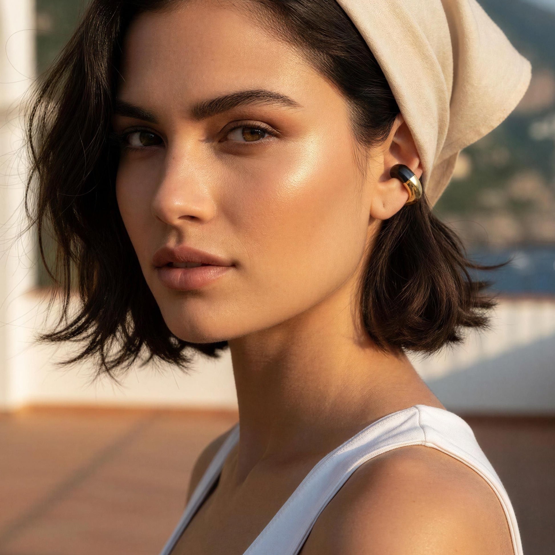 Woman wearing a beige headscarf and white top on a rooftop with Mountain View and the Gatsby Ear Cuff in Onyx 
