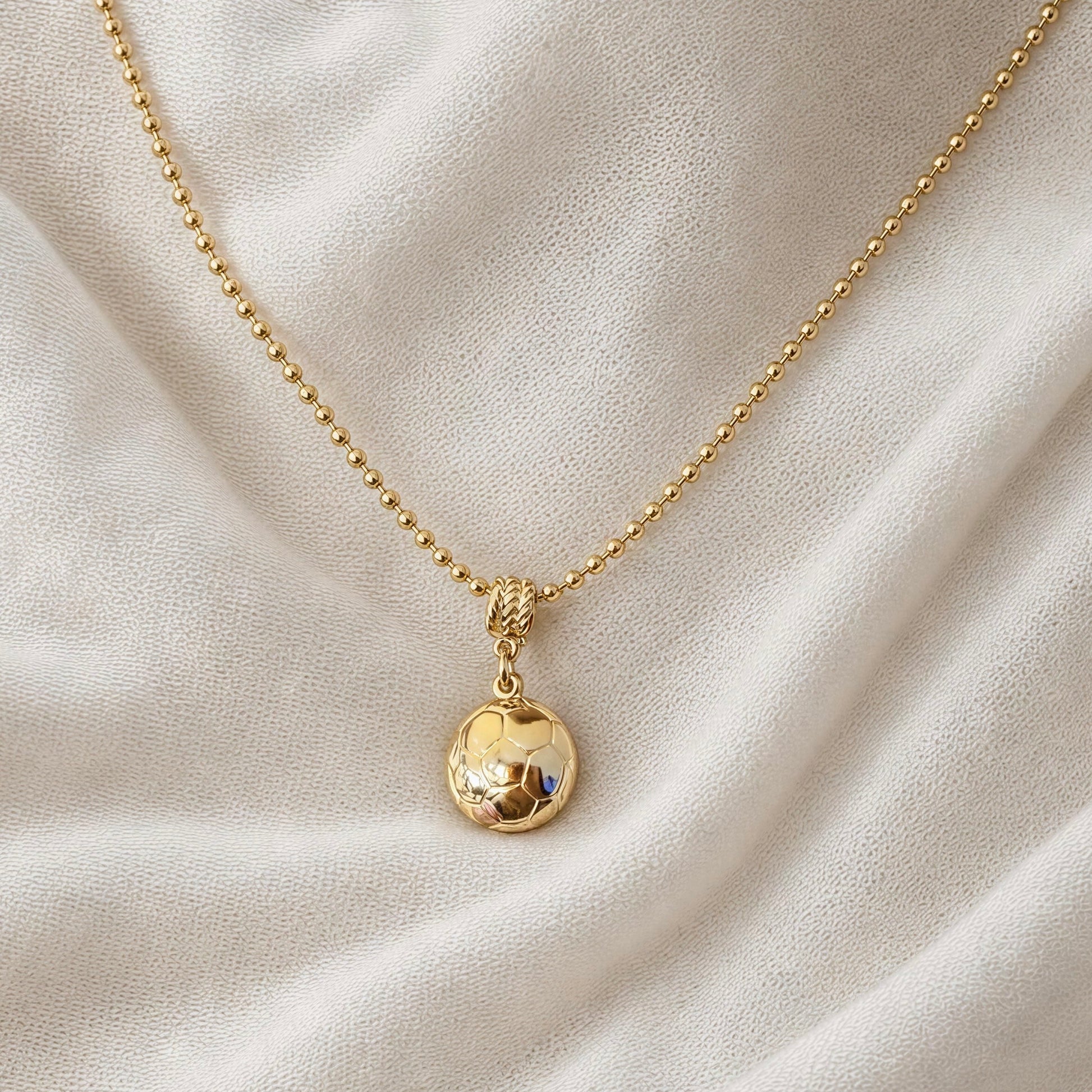 The Gol Dorado Necklace on a beige fabric background