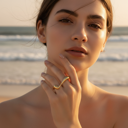 Woman on a beach wearing the Golden Cascade Ring with a blurred ocean background 