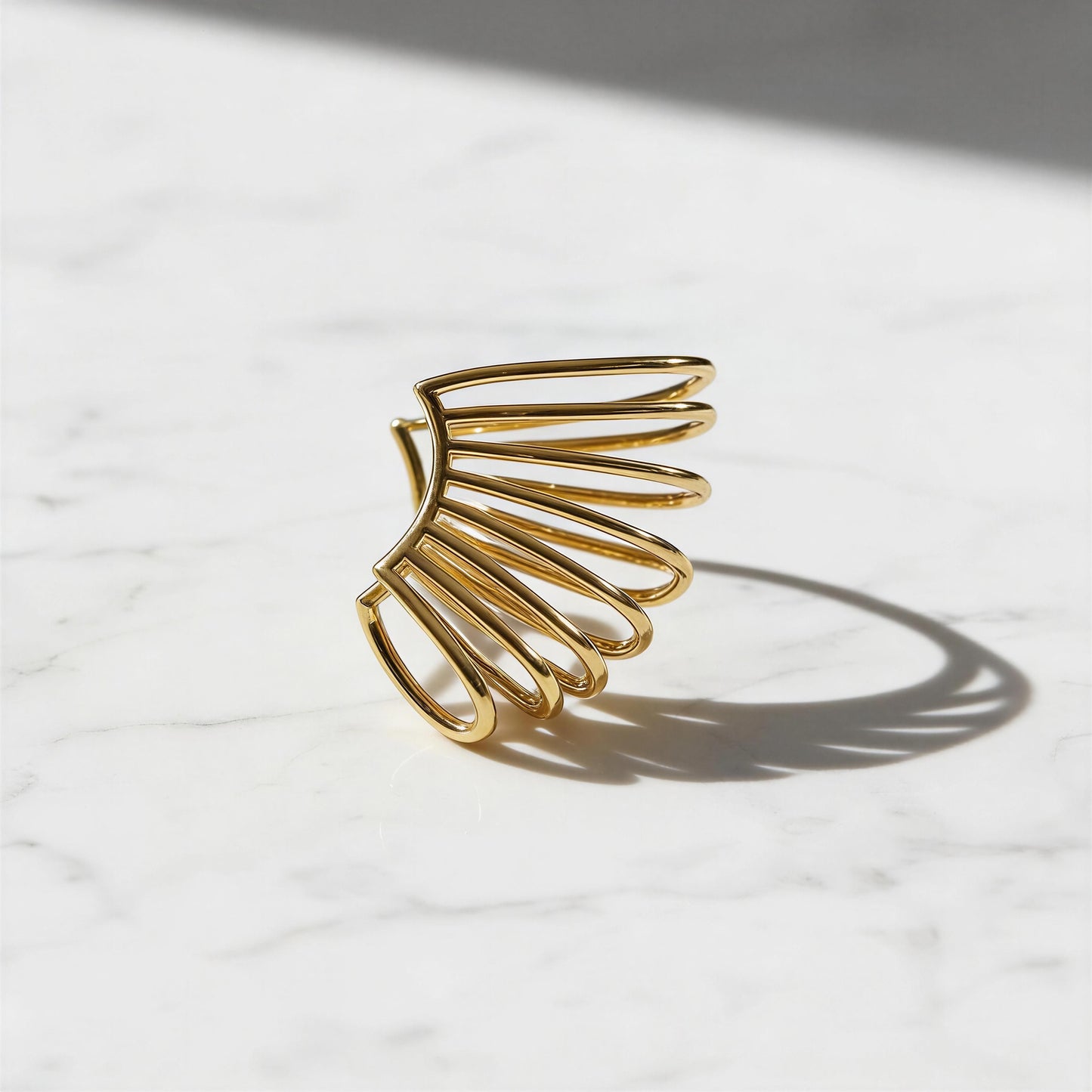 QGold wing-shaped ear cuff on a light marble surface