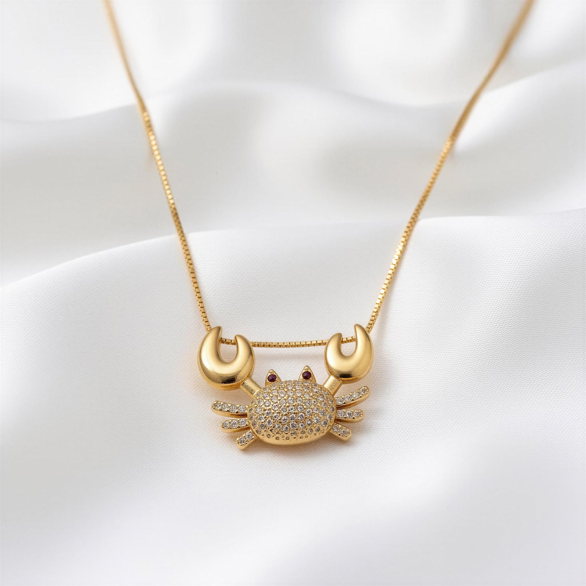 Gold crab-shaped pendant necklace on a white background