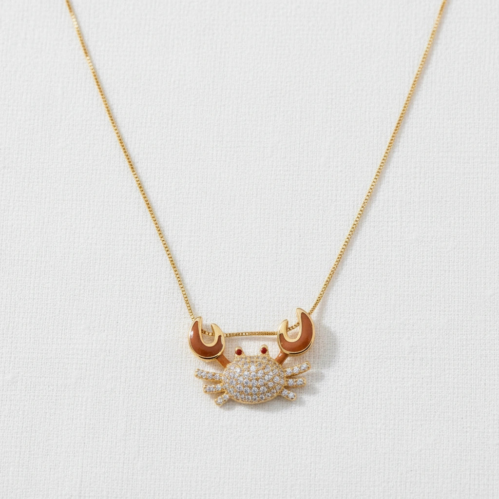 Gold crab-shaped pendant necklace on a white background from Chica Chica Jewelry