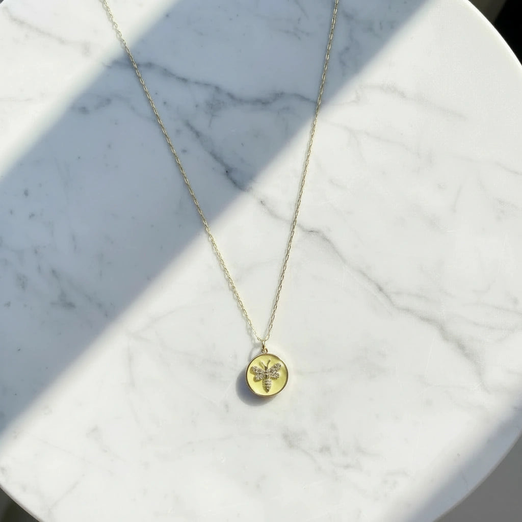 Gold Chica Chica Jewerly necklace with a was pendant on a marble surface