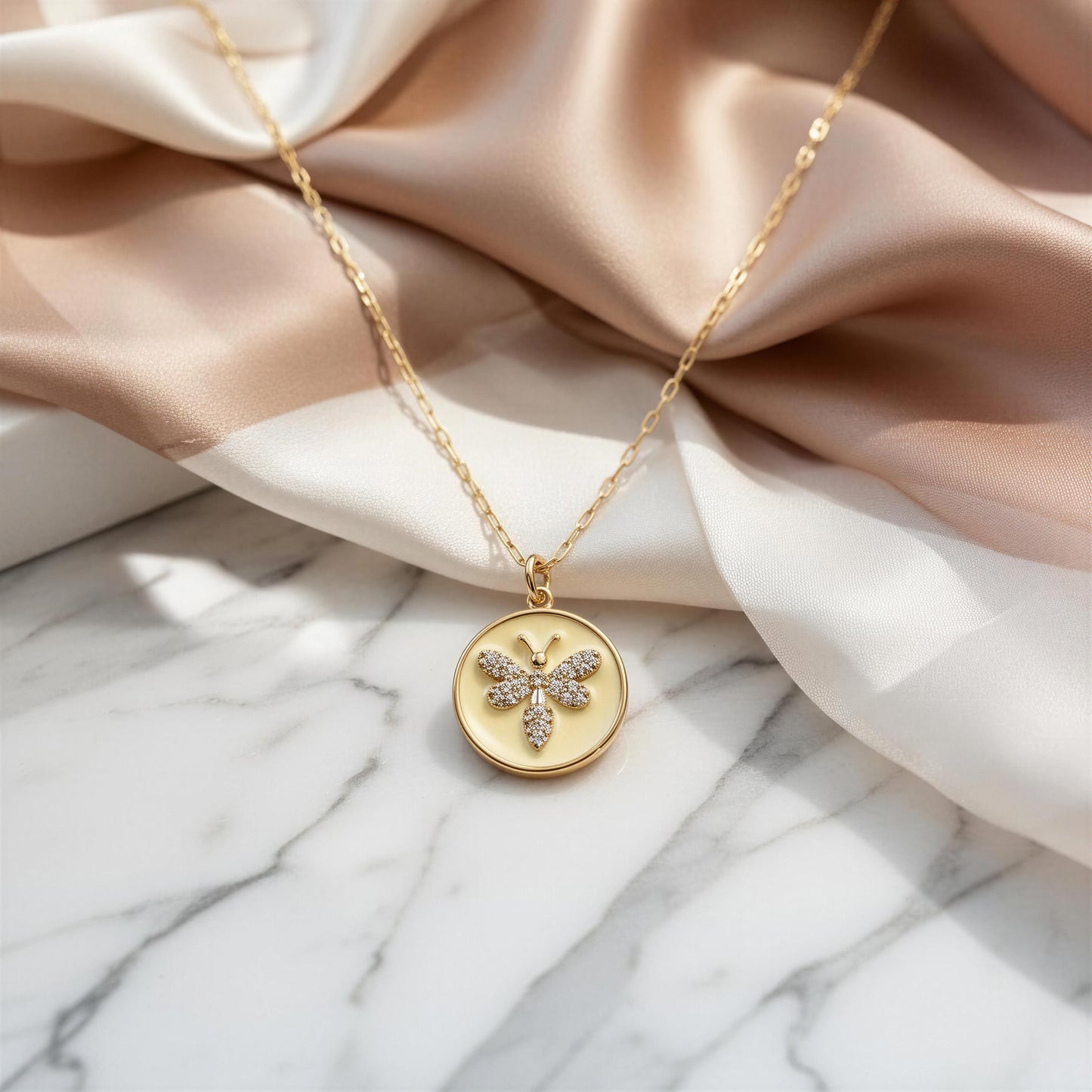 Gold necklace with a butterfly pendant on a marble surface with fabric background